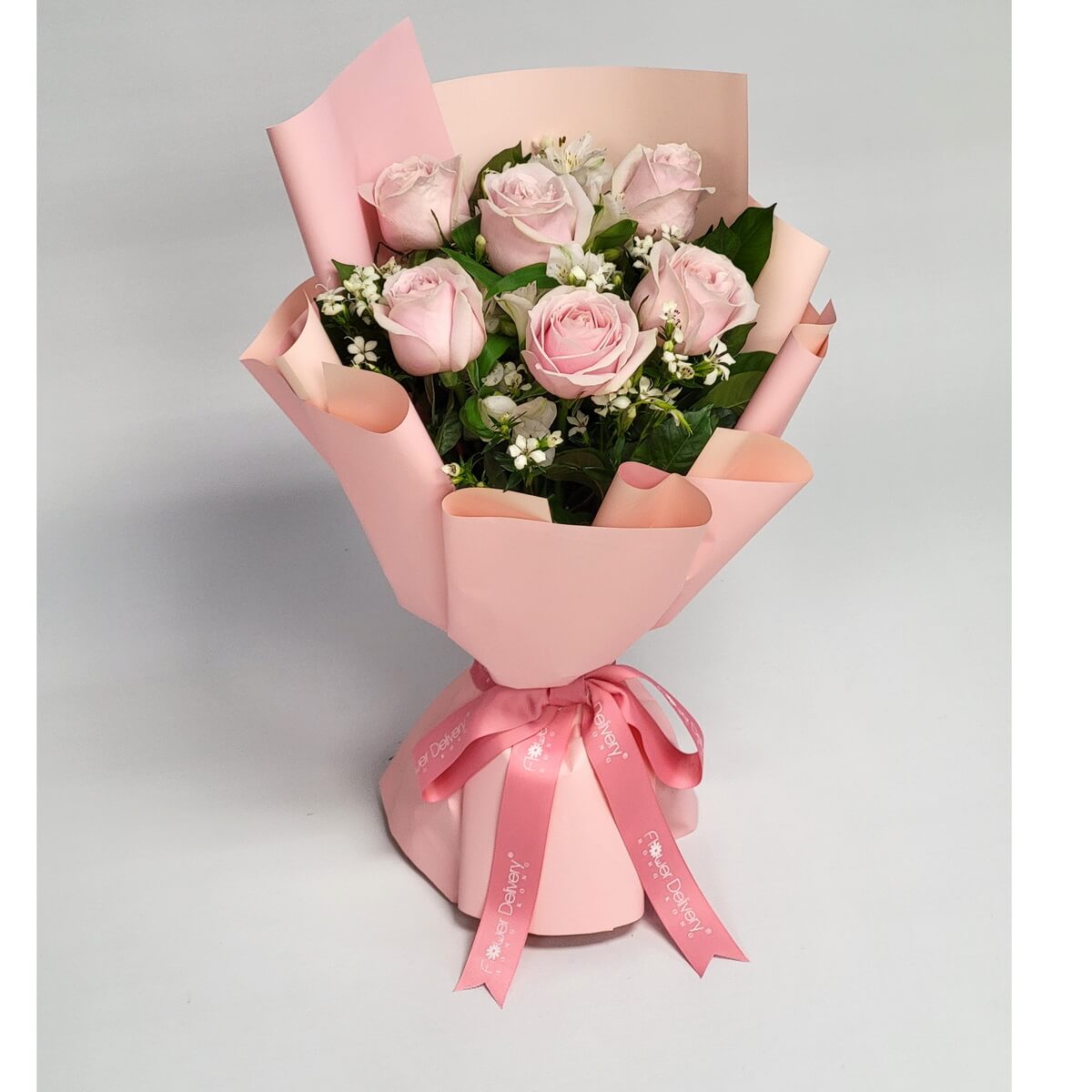 Hand-tied bouquet featuring pale pink roses, delicate white filler flowers, and foliage wrapped in pink 淡粉紅玫瑰、白色碎花及綠葉設計,採用粉紅包裝紙及絲帶,手綁花束造型柔美。