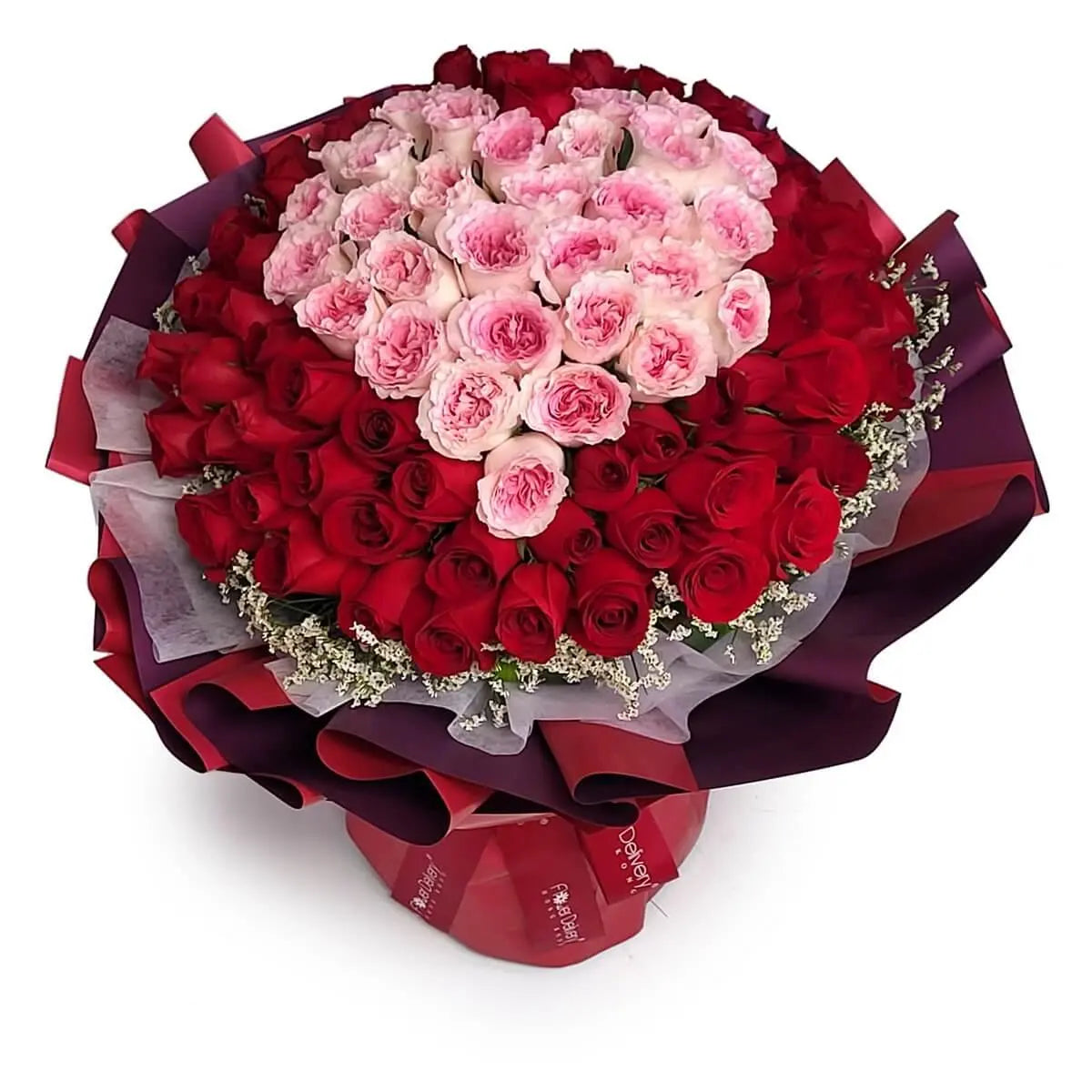 Bouquet featuring pink garden roses arranged in a heart, surrounded by red roses and baby's breath, wrapped in red and purple layers. 粉紅玫瑰心形排列,外圈為紅玫瑰及滿天星,配紅紫雙層包裝紙包裹,花束份量豐富。