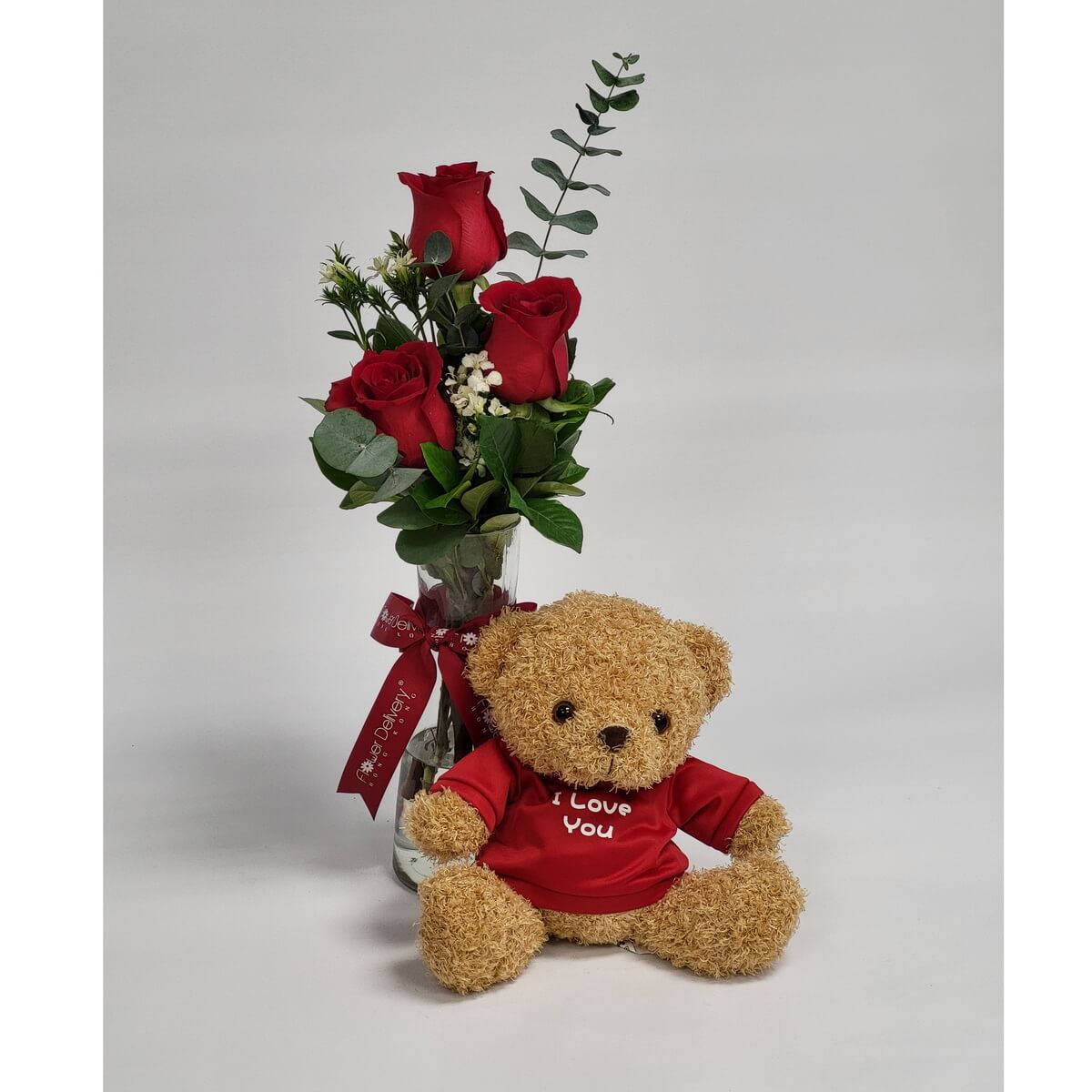 Glass vase with three red roses, white fillers, and greenery, accompanied by plush bear in red shirt 三枝紅玫瑰配白色碎花與綠葉插於玻璃瓶內,搭配身穿紅色“I Love You”字樣上衣的毛公仔。