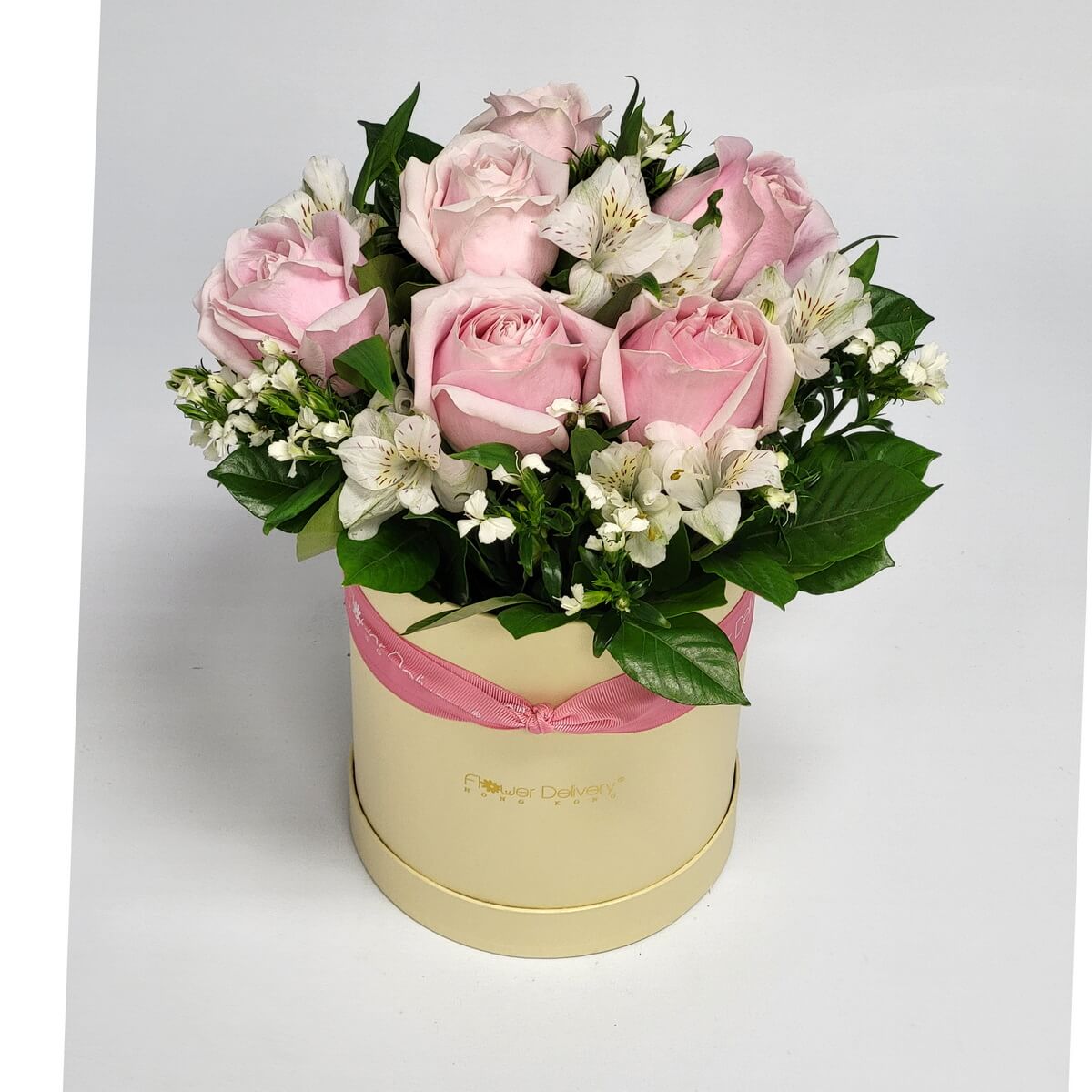 Cream round box with pale pink roses, white alstroemeria, and foliage 粉紅玫瑰與白百合草花材插於奶白色圓形花盒中,配搭綠葉,整齊緊湊設計。