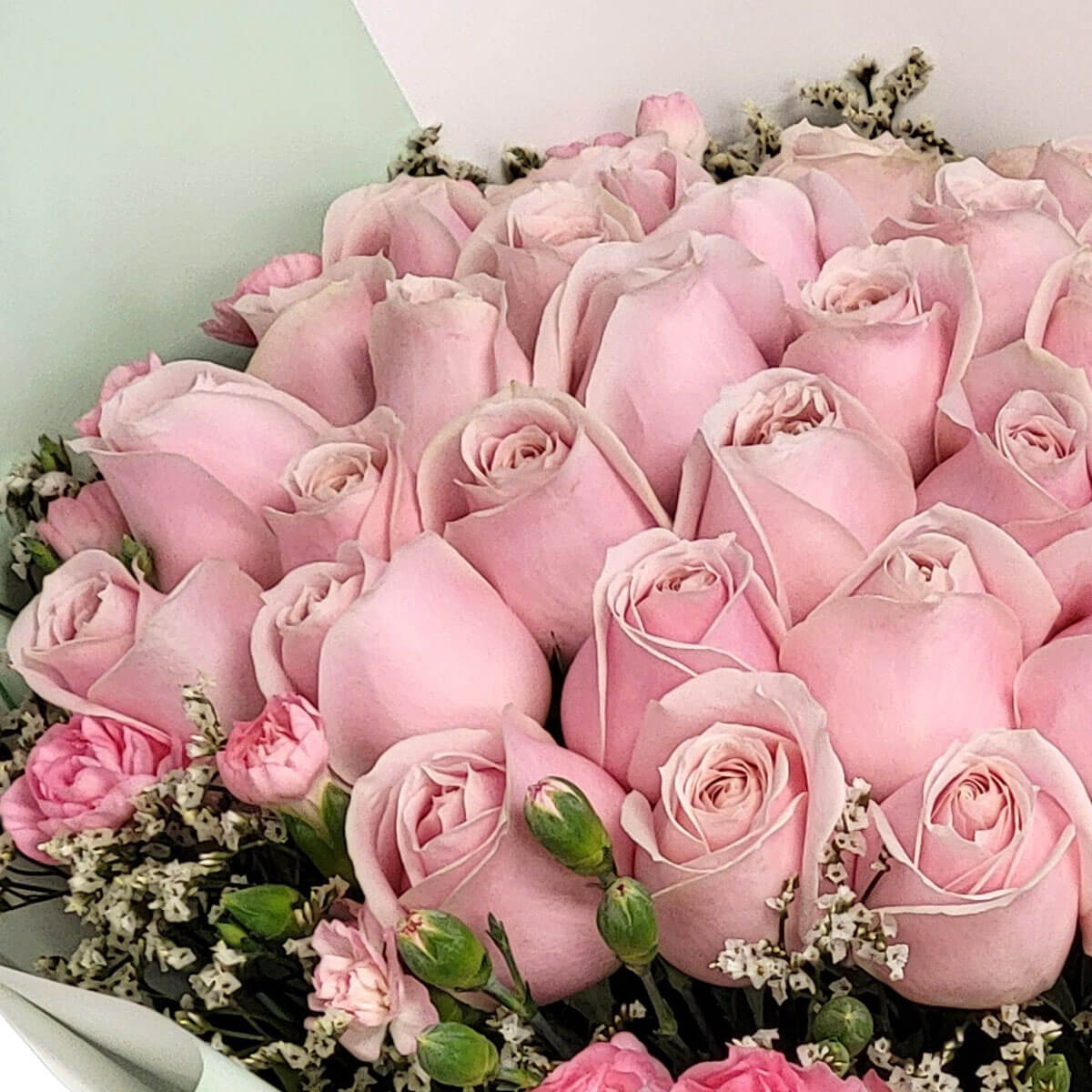 A graceful bouquet of pastel pink roses, mini carnations, and baby’s breath in mint wrapping 柔粉玫瑰搭配小康乃馨與滿天星,清新薄荷綠包裝更顯高雅。