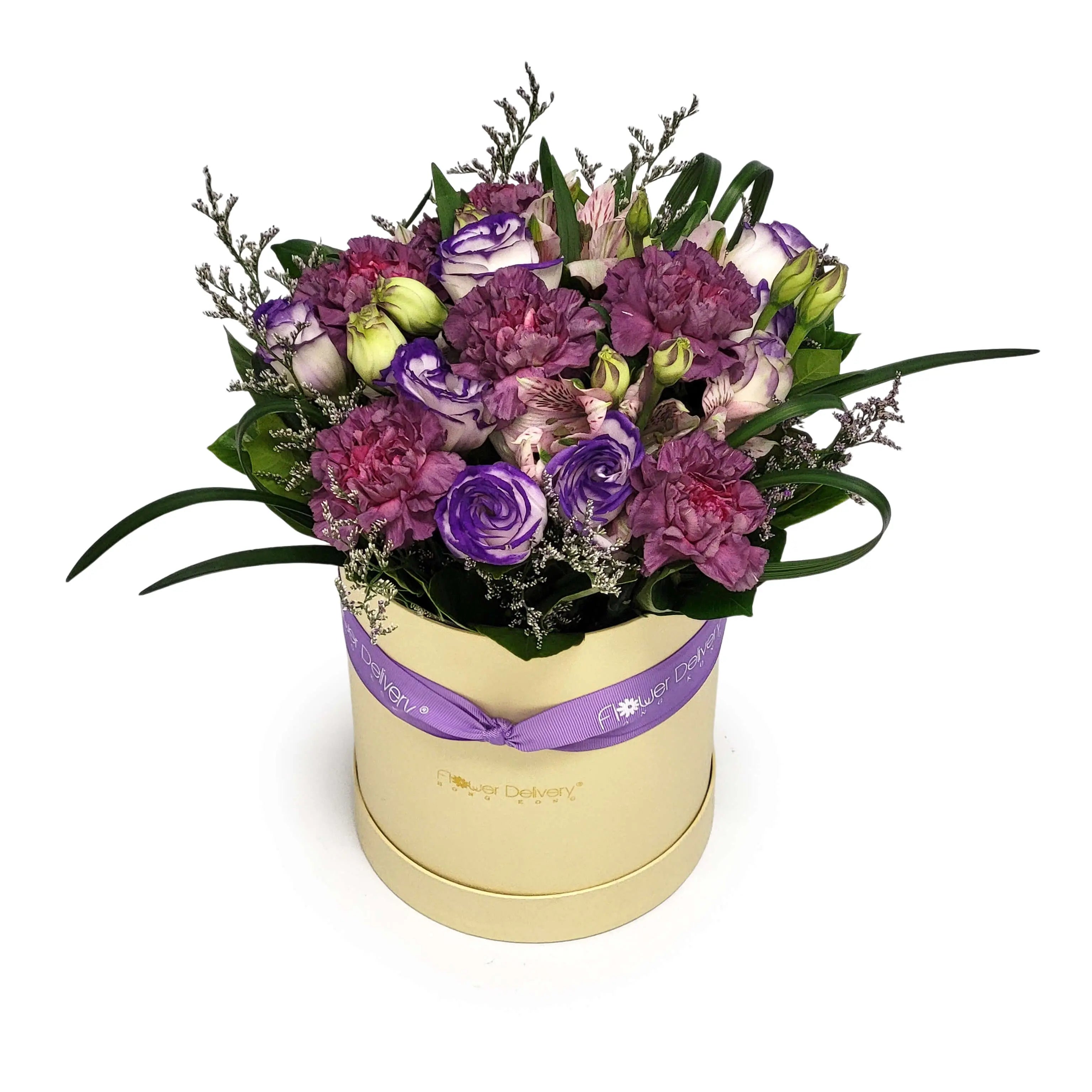 Cream hat box with purple lisianthus, mauve carnations, pink alstroemeria, accent filler, and greenery - 淡黃色花盒配紫色洋桔梗、粉紫康乃馨、粉紅六出花與襯葉,綴以紫色絲帶點綴。