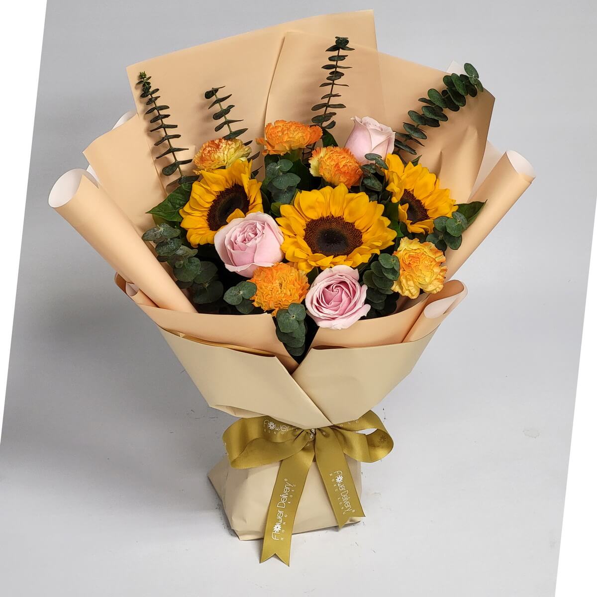 Wrapped bouquet of vibrant sunflowers, pastel pink roses, and ruffled orange carnations, accented with fresh eucalyptus 包裝花束含鮮黃向日葵、粉色玫瑰、橙色康乃馨與清新尤加利葉