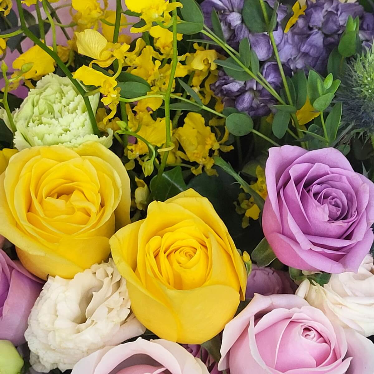 Close-up of yellow and lavender roses with white lisianthus, yellow oncidium orchids, and purple stock flowers | 黃色與淺紫玫瑰搭配白色洋桔梗、黃色文心蘭及紫色香豌豆特寫，花色鮮明層次豐富