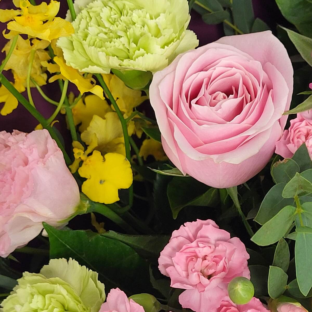 Close-up of pink rose with green carnation, pink lisianthus, and yellow oncidium orchids | 粉紅玫瑰配綠色康乃馨、粉紅洋桔梗及黃色文心蘭的細節特寫畫面。