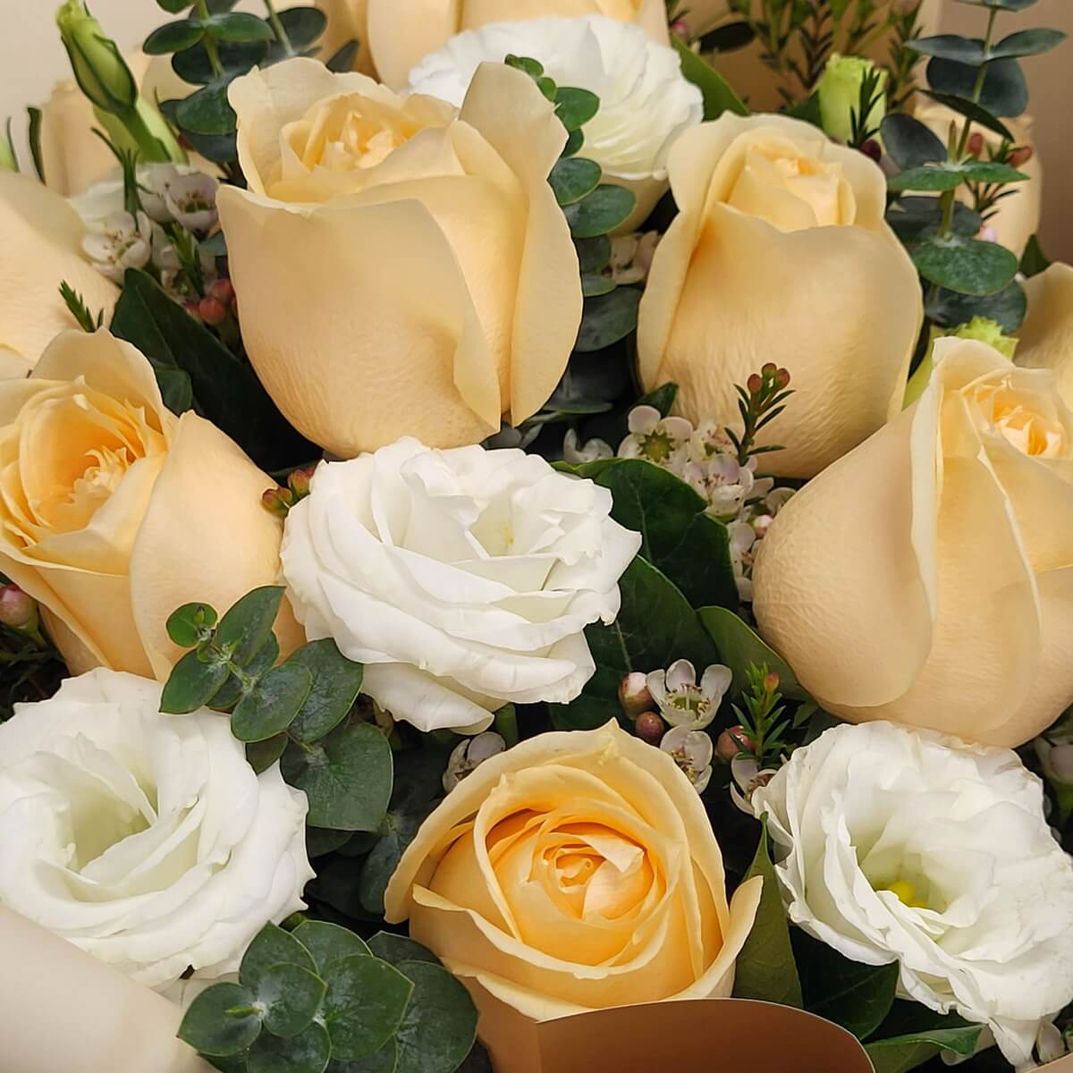 Detail view of champagne-toned roses and white lisianthus arranged with pink wax flowers and rounded eucalyptus leaves for a fresh, layered texture - 香檳玫瑰及白洋桔梗配粉蠟花及圓葉尤加利葉，層次感豐富特寫