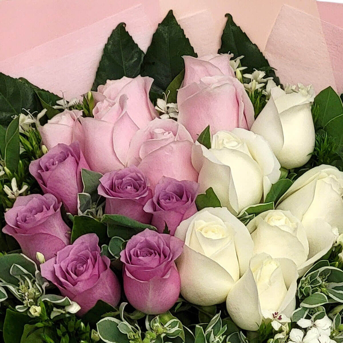 A bouquet of creamy white, pastel pink, and soft lavender roses surrounded by rich greenery 清新白、粉與薰紫玫瑰搭配濃綠葉材，傳遞溫柔與高雅。