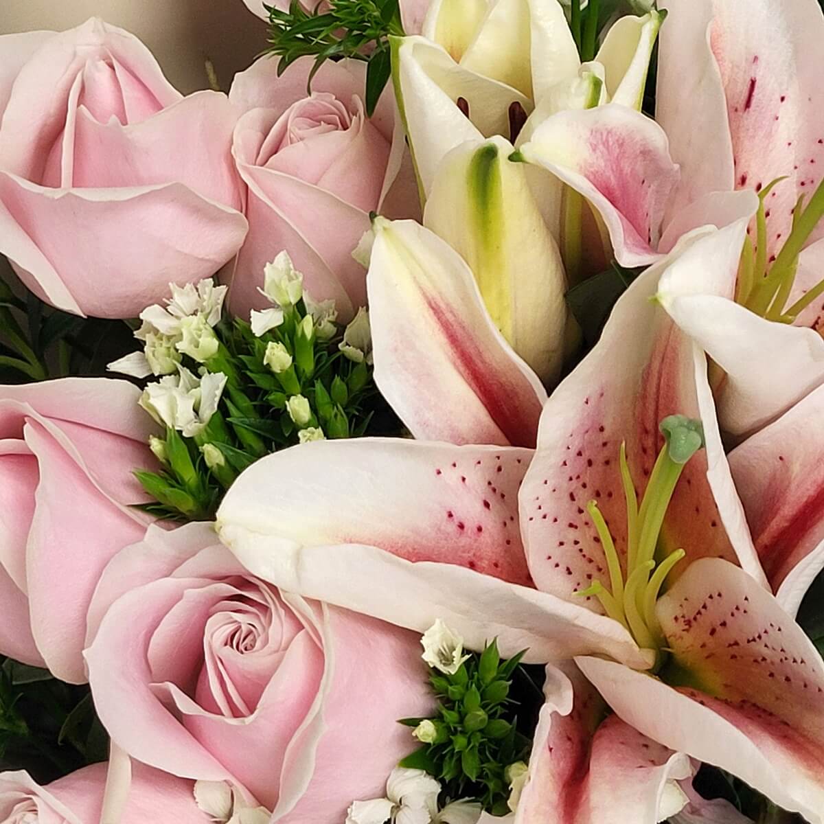 Detailed close-up of pink-spotted oriental lilies, pale pink roses, white filler flowers, and green accents 淡粉玫瑰、粉斑百合與白色配花及綠色襯葉細節特寫