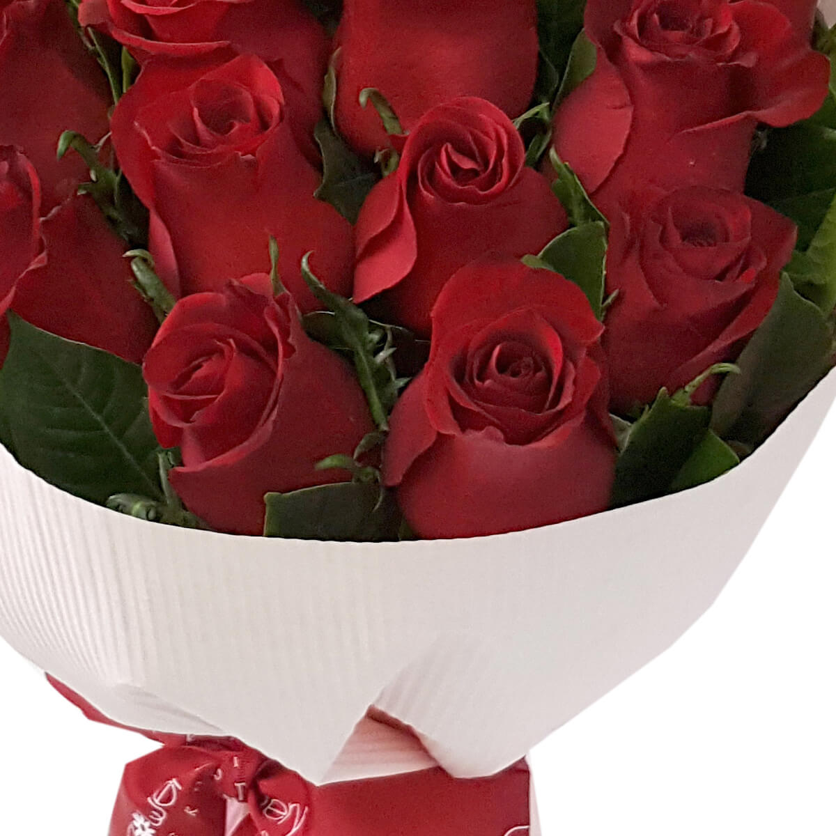 Elegant bouquet of red roses with green leaves, wrapped in textured white paper and finished with a red ribbon. 經典紅玫瑰花束，配綠葉，白色立體包裝紙與紅絲帶裝飾。