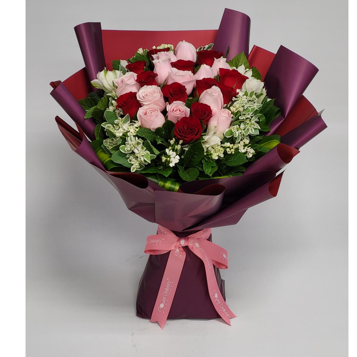 A lush bouquet of red and pink roses, wrapped in deep plum and red paper with soft pink ribbon. 深紅與粉玫瑰交織成愛的擁抱，搭配紫紅包裝與粉色緞帶，盡顯濃情蜜意。