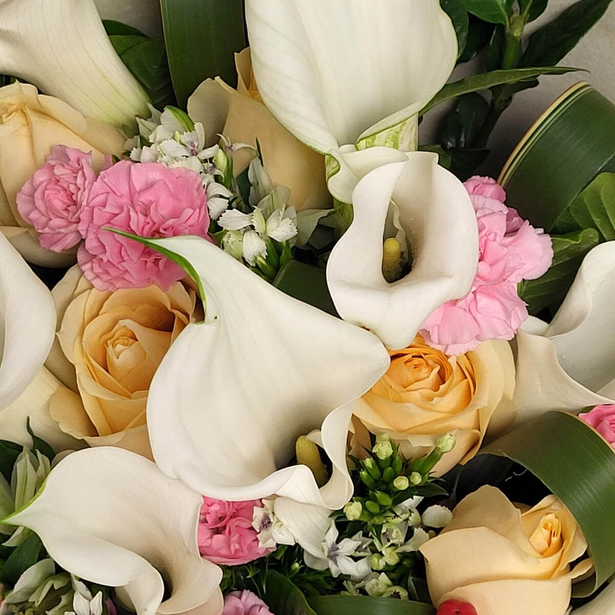 Close-up of white calla lilies, soft champagn  roses, pink carnations, and white alstroemeria with greenery accents | 白馬蹄蓮、
香檳色玫瑰、粉紅康乃馨與白色六出花特寫，搭配綠葉點綴