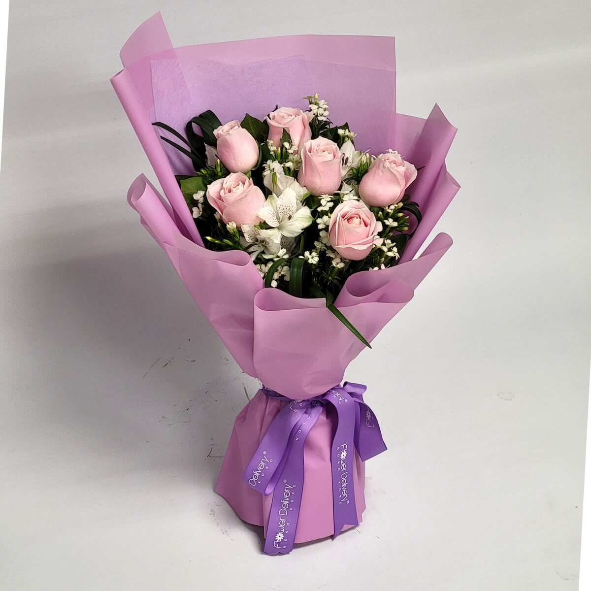 Elegant pink bouquet featuring blush roses, white alstroemeria, and white dianthus, wrapped in matte pastel pink and tied with purple ribbon 粉紅玫瑰、白六出花與石竹花組成的花束，以粉紫包裝及紫色絲帶裝飾