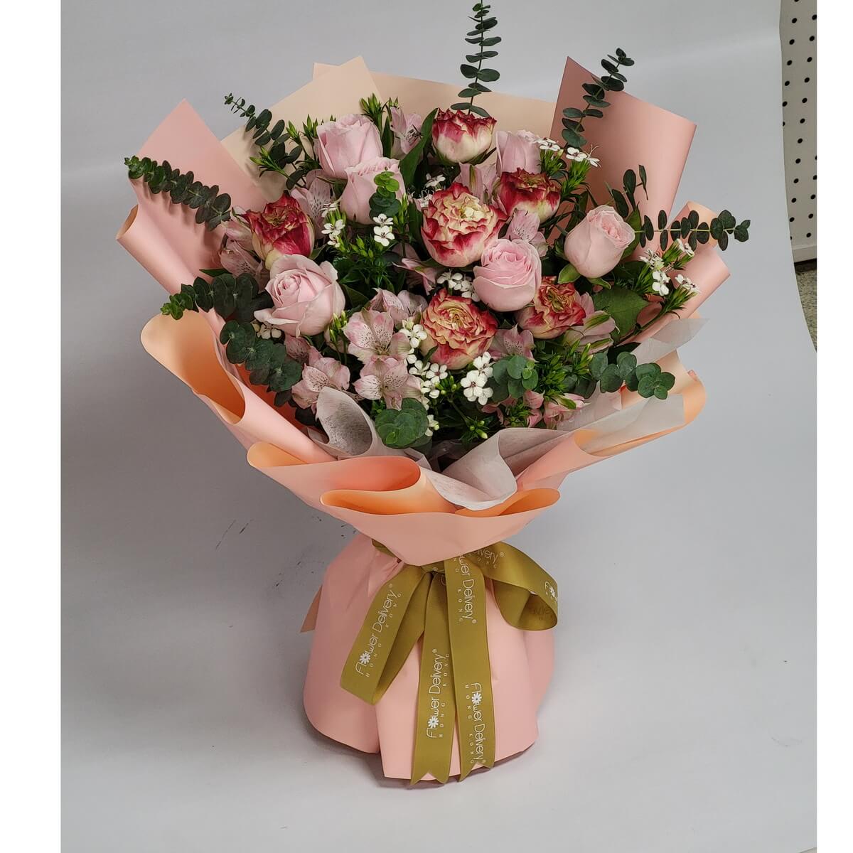 A graceful bouquet of blush pink roses, red-tipped carnations, alstroemeria, waxflowers, and eucalyptus, wrapped in peach and blush paper with a golden ribbon. 柔和復古色調，傳遞溫柔與雅緻的祝福。