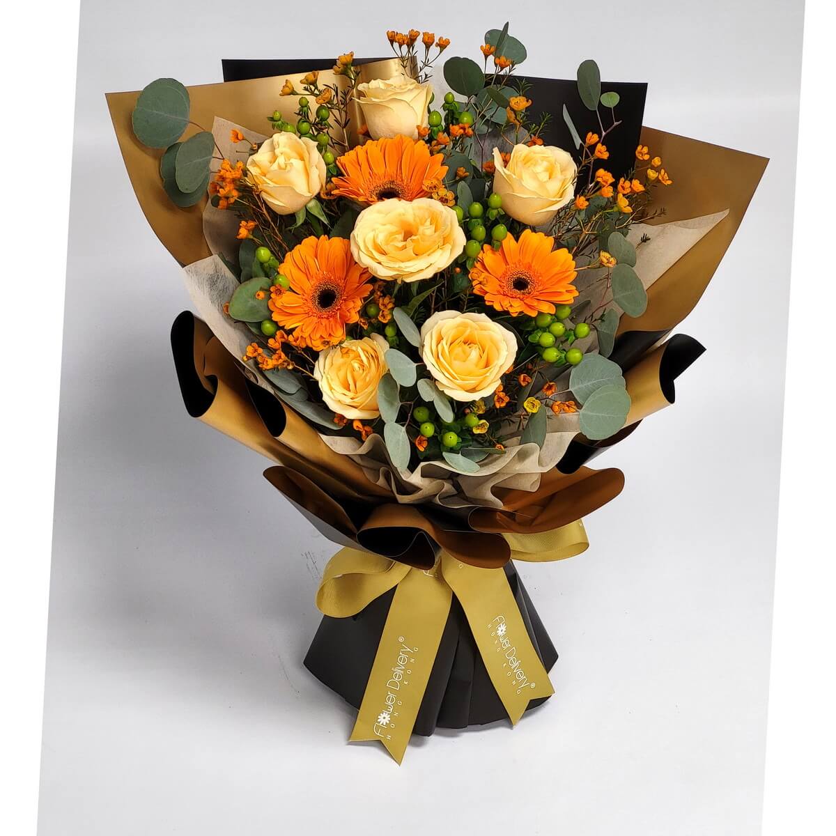 A radiant bouquet of champagne roses, bright orange gerberas, and lush eucalyptus, wrapped in elegant black and bronze paper with a gold ribbon. 活力橙與香檳玫瑰交織，猶如秋日暖陽，綻放溫柔與熱情。