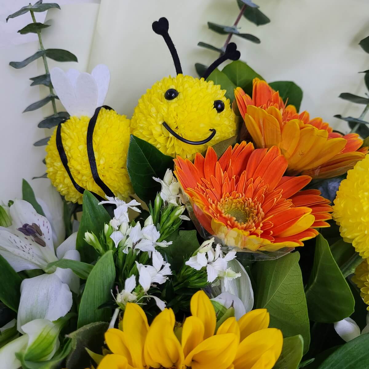 Bee-shaped button chrysanthemums with gerberas and lilies 乒乓菊製成蜜蜂造型，搭配橙色非洲菊、白百合及向日葵。