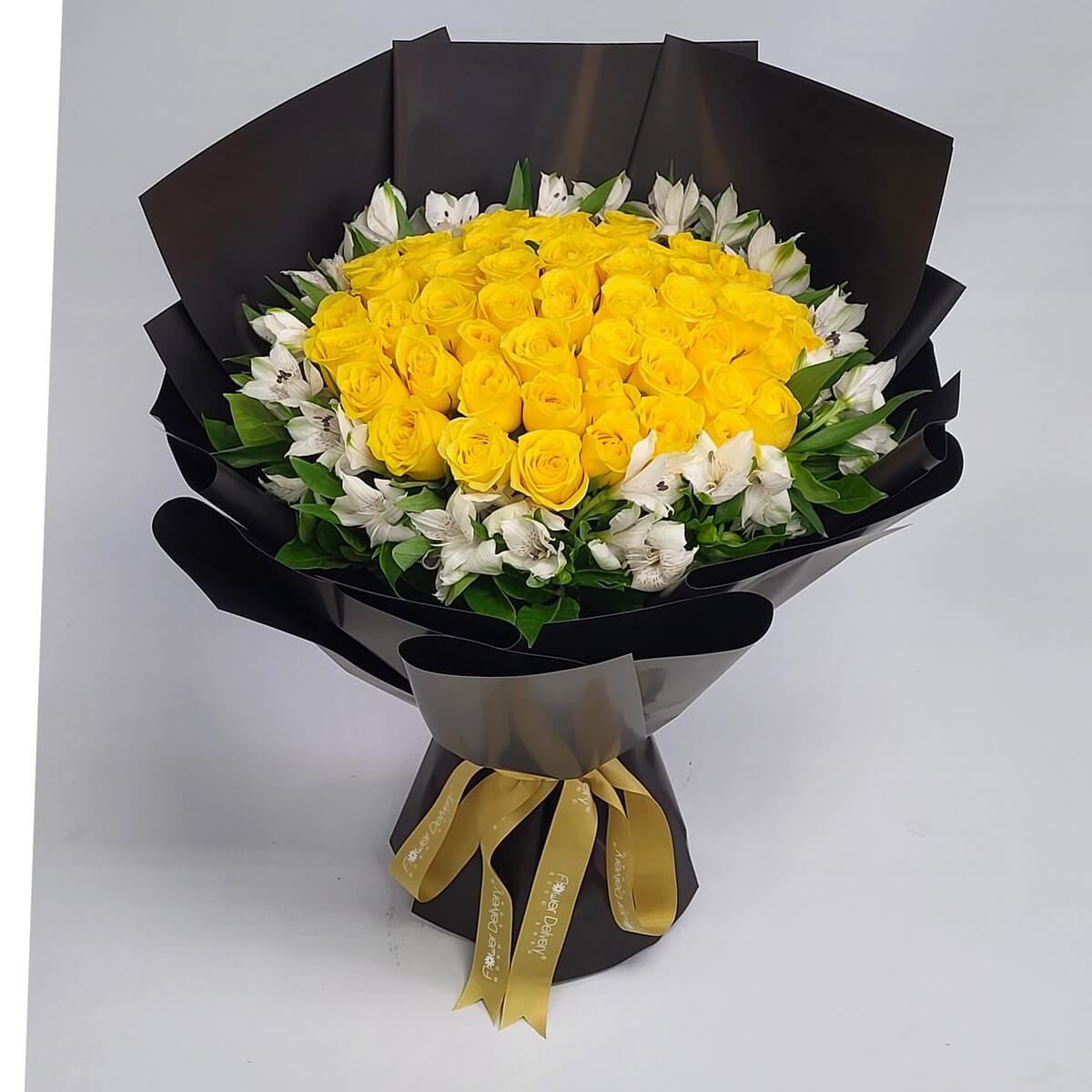 Bouquet of vibrant yellow roses surrounded by white alstroemeria, arranged in a sleek black wrap with a champagne gold ribbon. 鮮黃玫瑰搭配白色六出花，黑色包裝紙與香檳金絲帶襯托出高貴氣質。