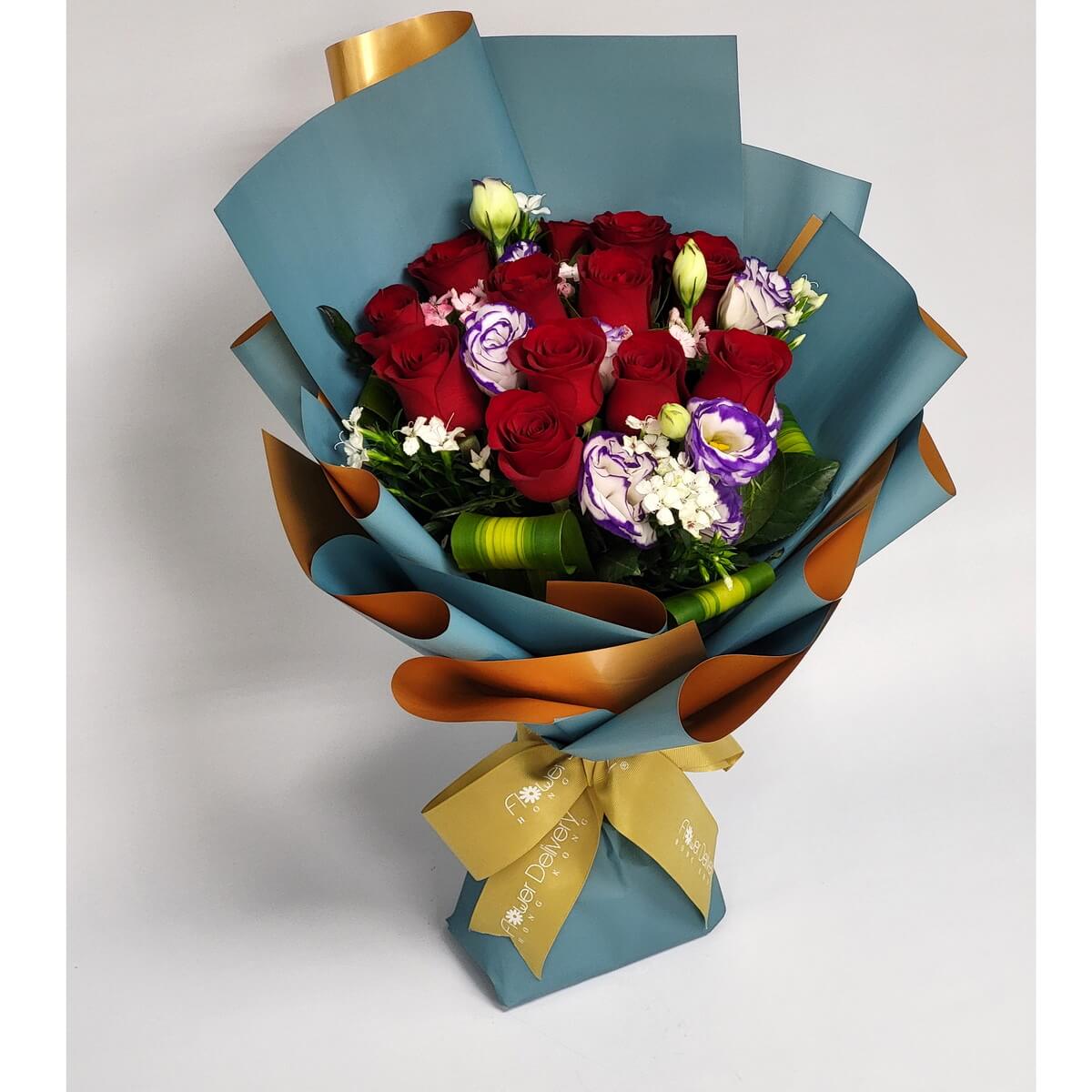 Elegant bouquet with red roses, purple-white lisianthus, and white accent blooms, wrapped in matte teal and gold paper with a golden ribbon. 紅玫瑰與紫白桔梗交織，金青包裝，典雅奪目。