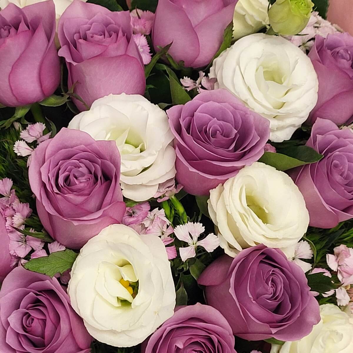 Close-up floral detail featuring lavender roses, white lisianthus, and delicate pink dianthus accents, tightly arranged with layered petals and fresh green foliage 紫色玫瑰、白色洋桔梗及粉紅石竹近距離花藝細節