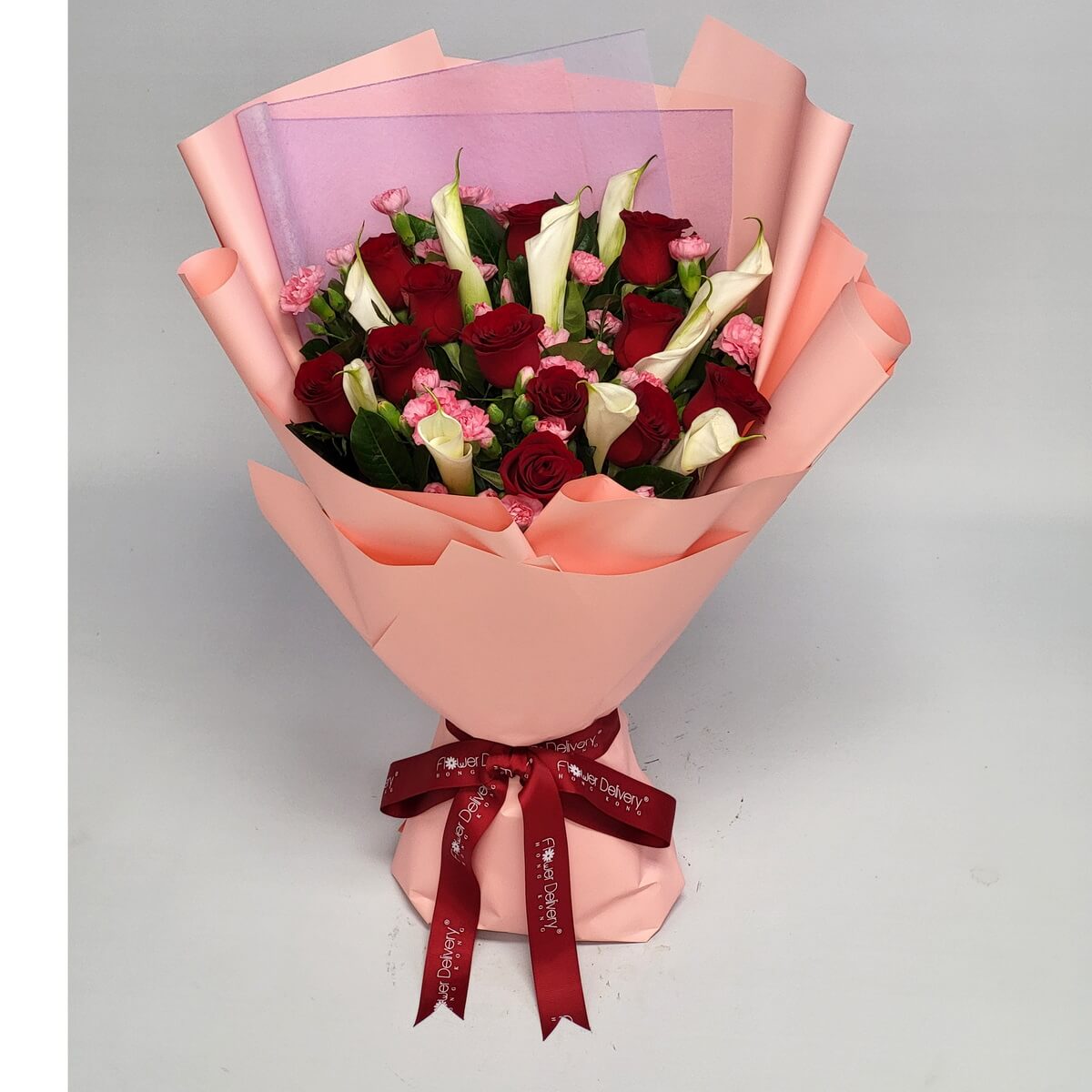 Elegant bouquet wrapped in pink paper, featuring red roses, white calla lilies, pink spray carnations, and lush greenery 粉色包裝花束含紅玫瑰、白馬蹄蘭、粉迷你康乃馨與濃密綠葉搭配