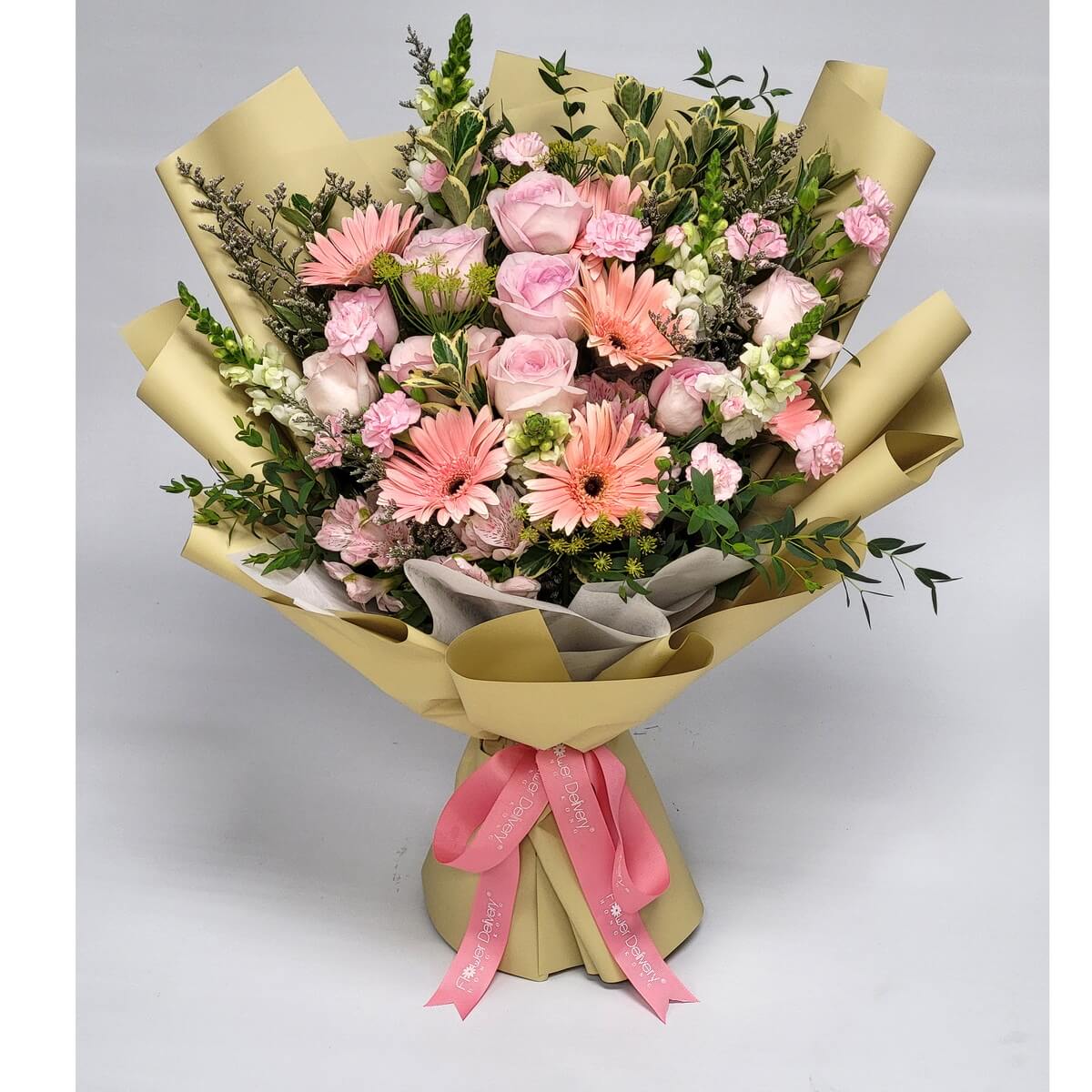 Blush pink roses, gerberas, and carnations nestled in soft yellow wrapping, accented with greenery and a bright pink ribbon. 粉玫瑰、粉紅太陽花與康乃馨交織成浪漫花束，淡黃色包裝襯托清新自然美感。