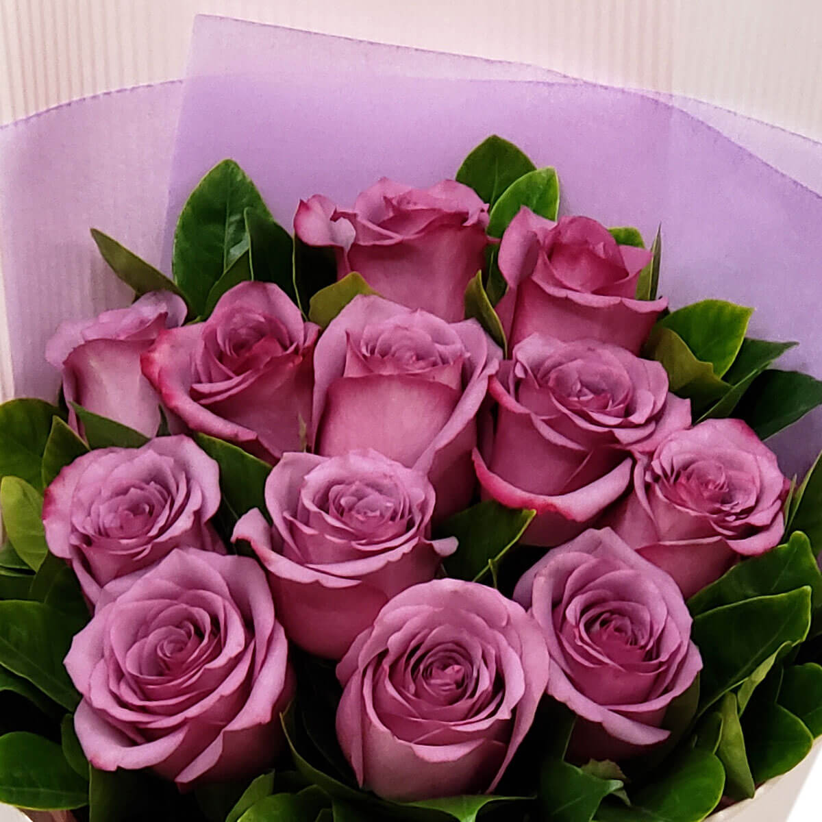 Full bouquet of twelve lavender roses with layered green leaves and light purple wrapping, viewed from above - 十二枝紫羅蘭玫瑰與層次綠葉及淺紫包裝的上視圖花