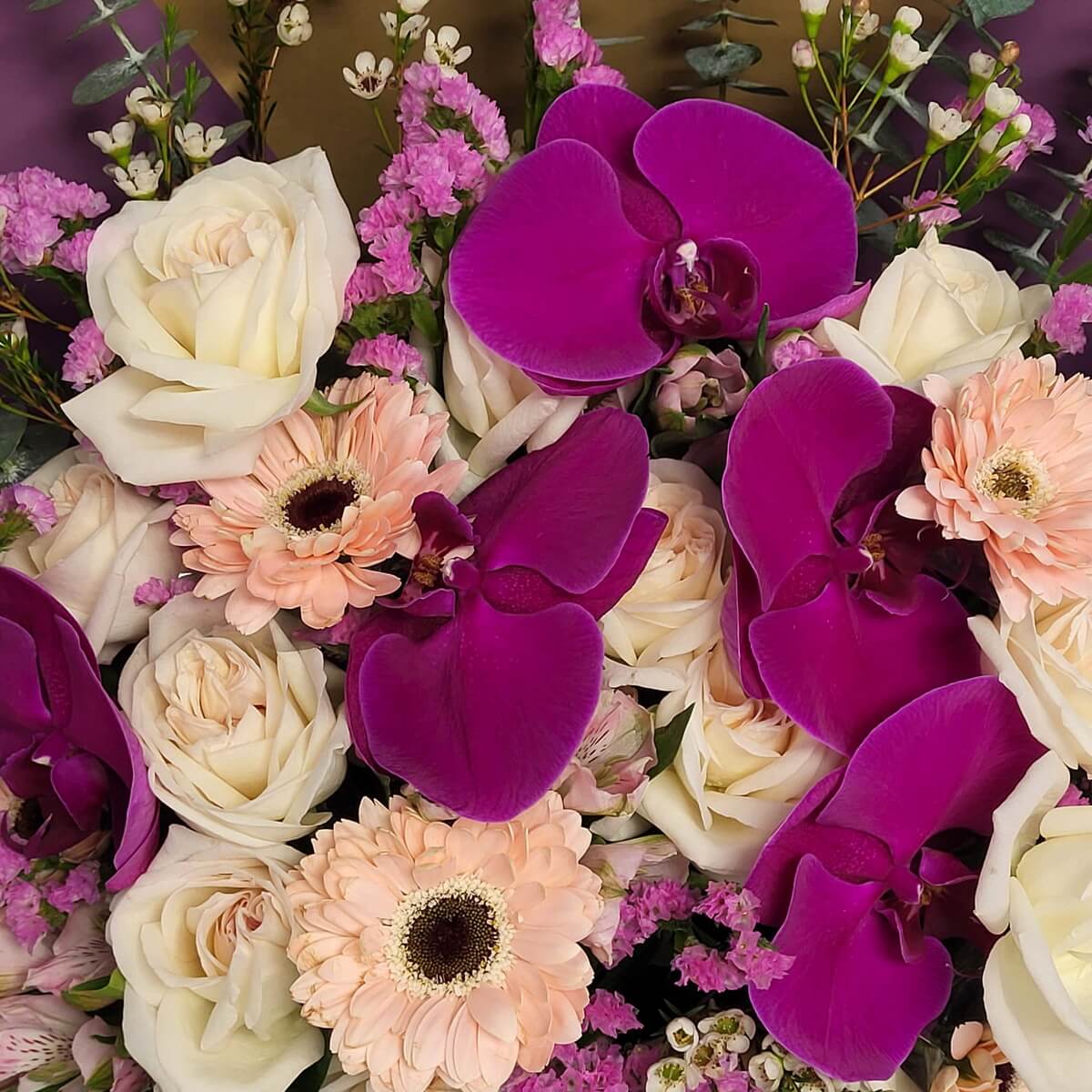 Detailed close-up showing fuchsia phalaenopsis orchids, cream roses, pale peach gerberas, waxflowers, pink statice, and eucalyptus 紫紅蝴蝶蘭、奶白玫瑰、蜜桃非洲菊、蠟花、粉色勿忘我與尤加利葉的細節特寫