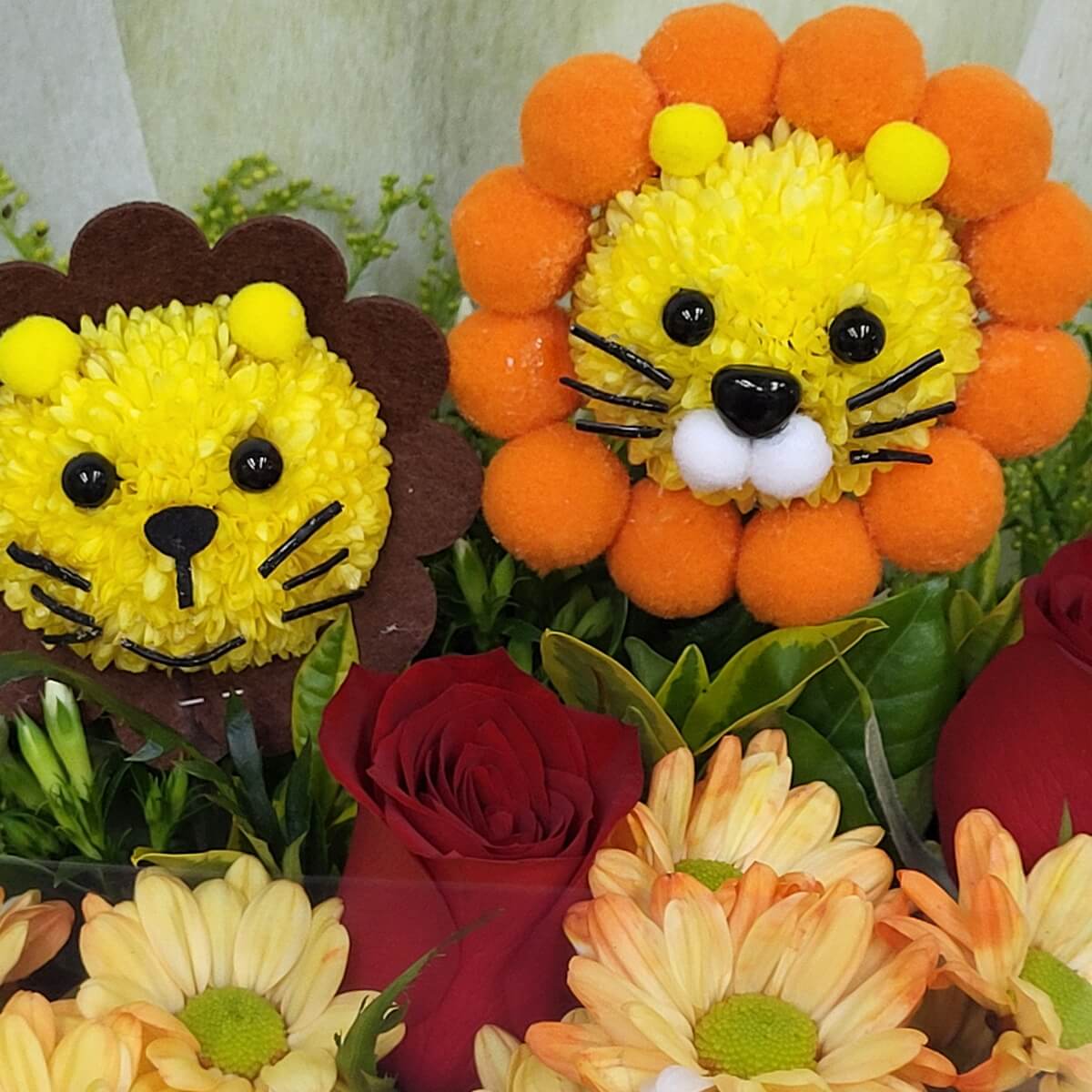 Lion face floral arrangements made with yellow button chrysanthemums, accented by orange pom-poms, red roses, and peach chrysanthemums | 獅子造型花藝以黃色乒乓菊製成，搭配橙色毛球、紅玫瑰及桃色菊花特寫，色彩活潑鮮明