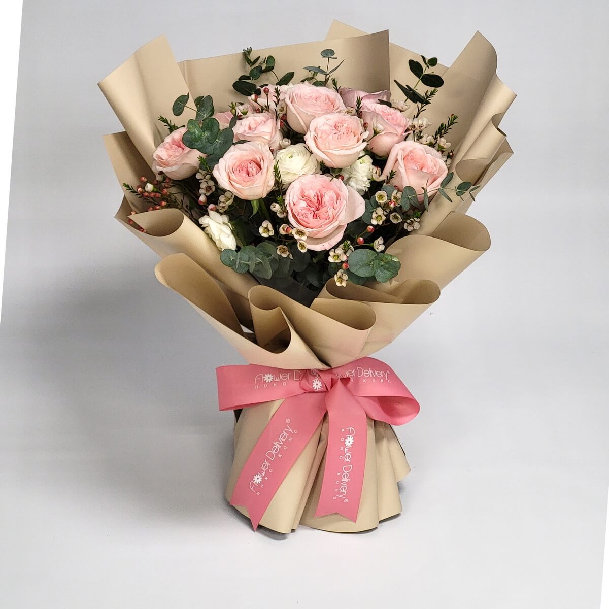 A graceful bouquet of blush pink and ivory roses, accented with wax flowers and eucalyptus, wrapped in champagne paper with a pink satin ribbon. 淡粉與象牙白玫瑰搭配尤加利與花蠟，包裹於香檳色紙中，系上粉紅緞帶，溫柔浪漫。
