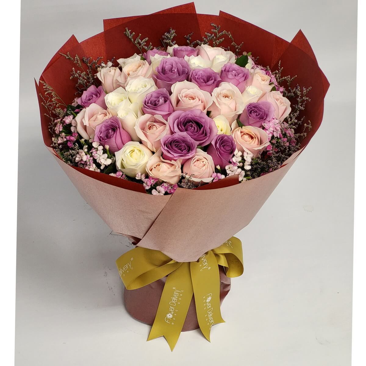 Lavender, blush pink, and ivory roses arranged in a dome-shaped bouquet with pink baby’s breath, wrapped in pink and burgundy paper – 紫、粉與奶白玫瑰搭配粉色滿天星，包裹於粉紅與酒紅紙內