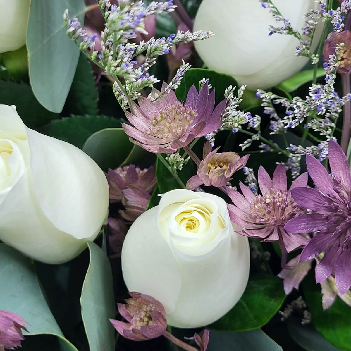 Detail view showing ivory rose blooms framed by mauve astrantia and clusters of fine purple limonium stems 白玫瑰特寫，搭配淡紫星狀花與紫情人草小花組成層次豐富構圖