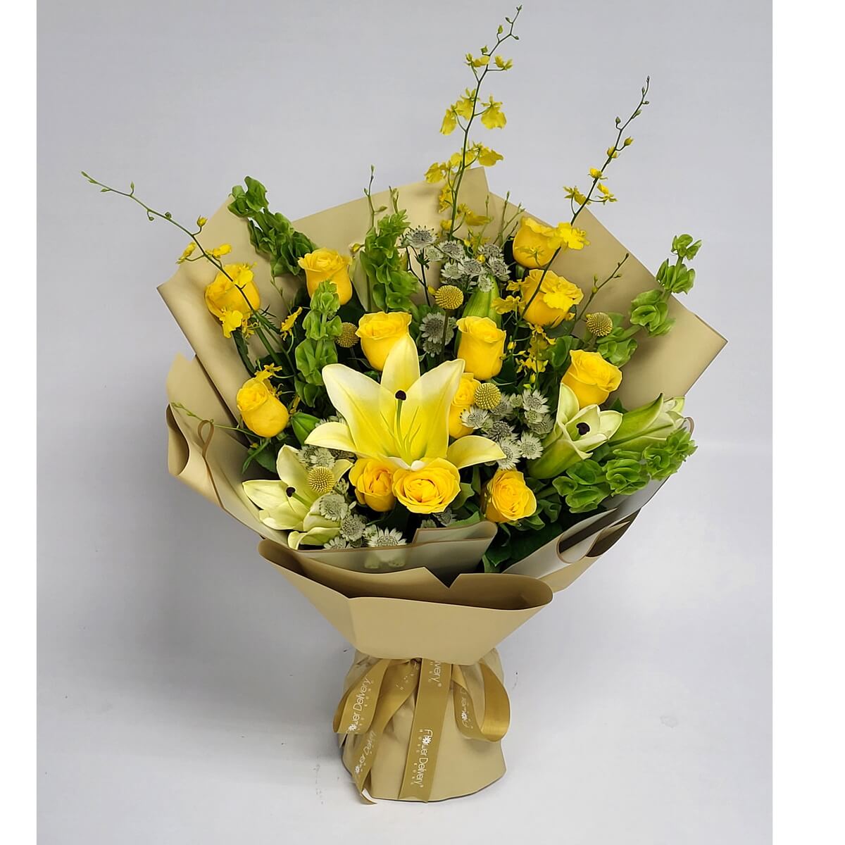 Vibrant yellow roses and lilies with accents of green and golden fillers, wrapped in golden-beige paper and a matching ribbon. 鮮黃玫瑰與百合，搭配金綠點綴，金米色包裝，明亮又暖心。