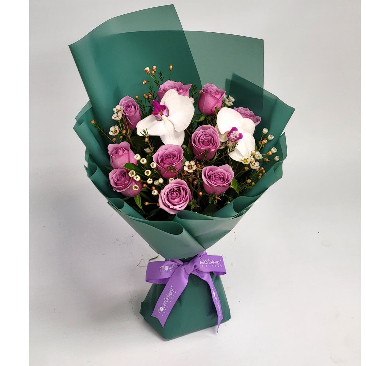 Elegant bouquet of lavender roses, white orchids with pink centers, and waxflowers, wrapped in green paper and tied with a purple ribbon – 優雅花束由淺紫玫瑰、粉心白蘭花與蠟花組成，綠色包裝搭配紫絲帶
