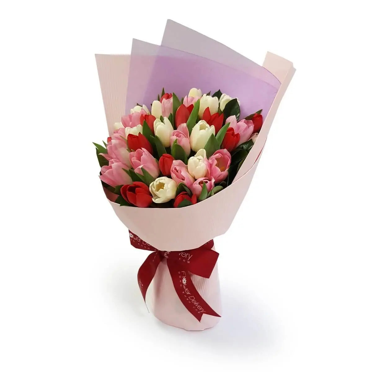 Hand-tied bouquet of red, pink, and white tulips with green leaves, wrapped in pastel pink and translucent lavender paper with a red ribbon. 紅、粉、白鬱金香手綁花束，配綠葉與粉紫包裝，綁紅絲帶。