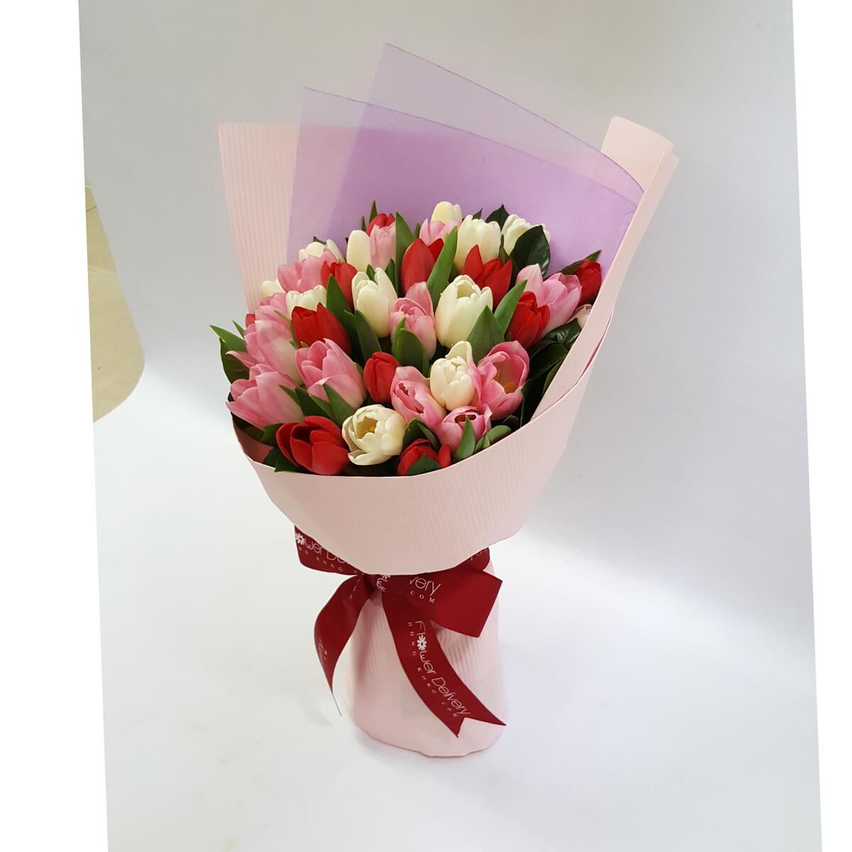 Mixed bouquet of red, white, and pink tulips, wrapped in soft pink and lavender-toned paper with a red ribbon. Cheerful and graceful. 紅白粉鬱金香花束，淡粉與紫色包裝襯托出清新甜美的氣質，洋溢著幸福感。