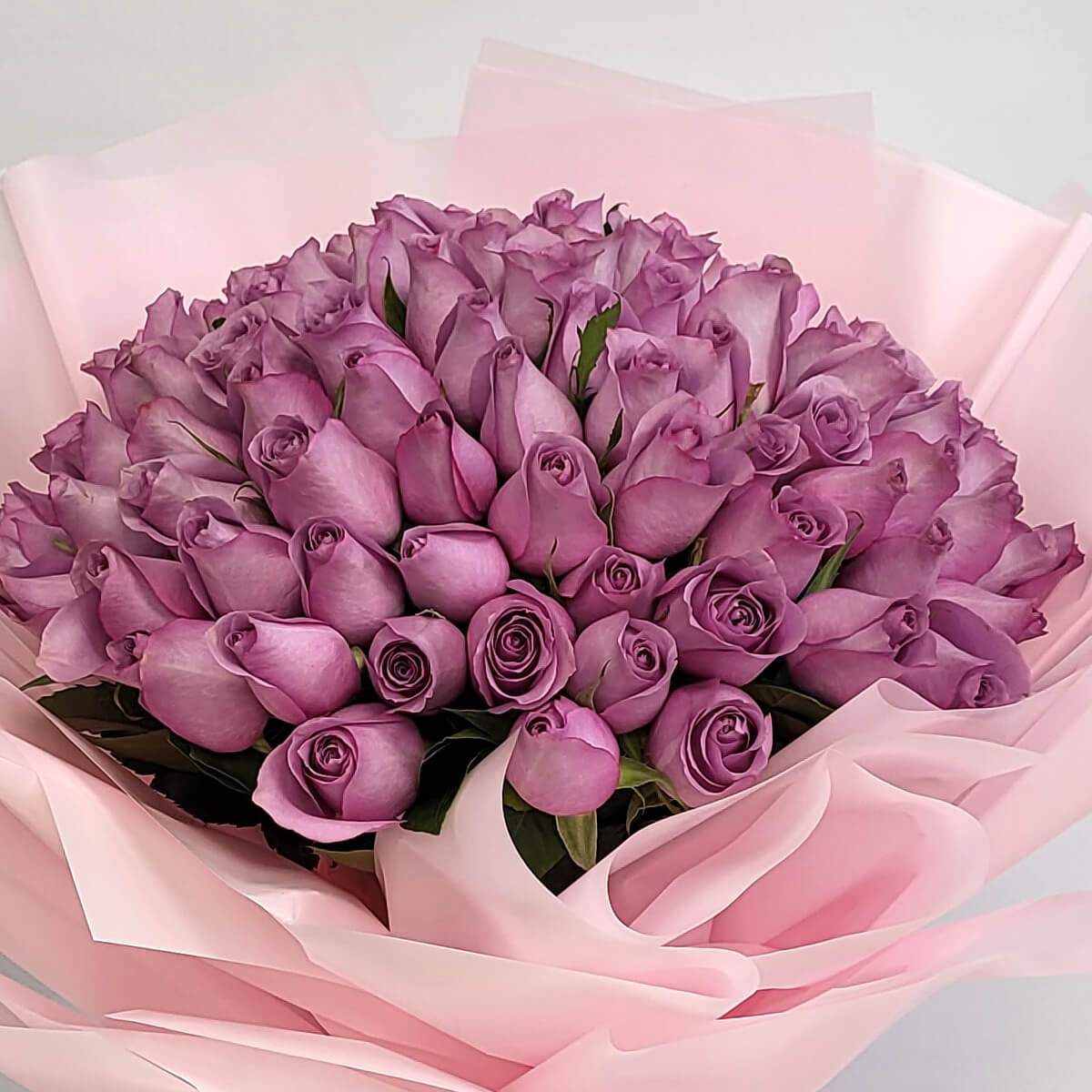 Tightly packed lavender roses in a rounded bouquet style, wrapped with layered pink paper - 圓形淡紫玫瑰花束，配分層粉紅包裝紙