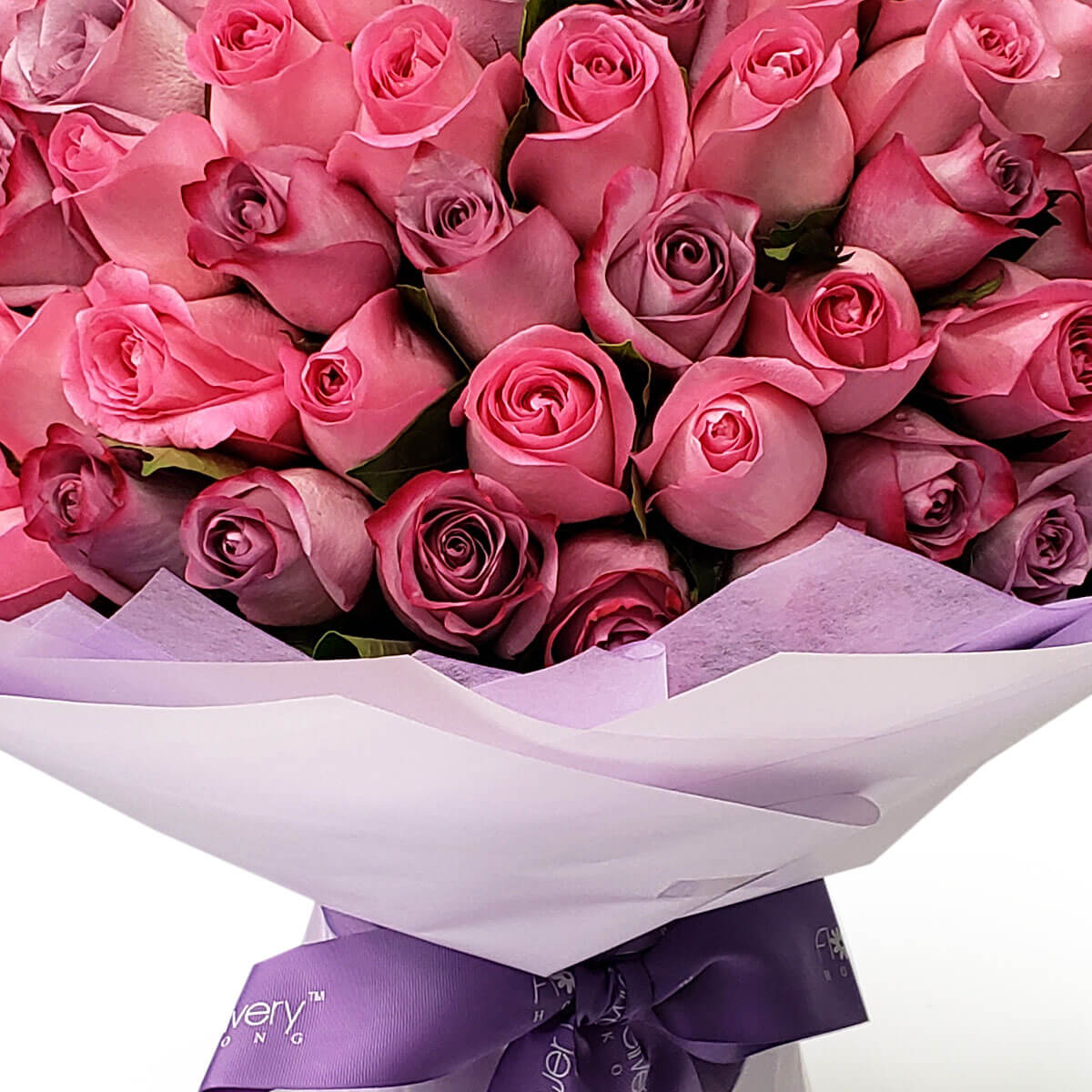 Full view of a round bouquet with layered pink and mauve roses, wrapped in white and lavender paper and finished with a satin ribbon - 粉紅與藕紫玫瑰層層排列，白色與淡紫包裝紙及緞帶完整包裹花束