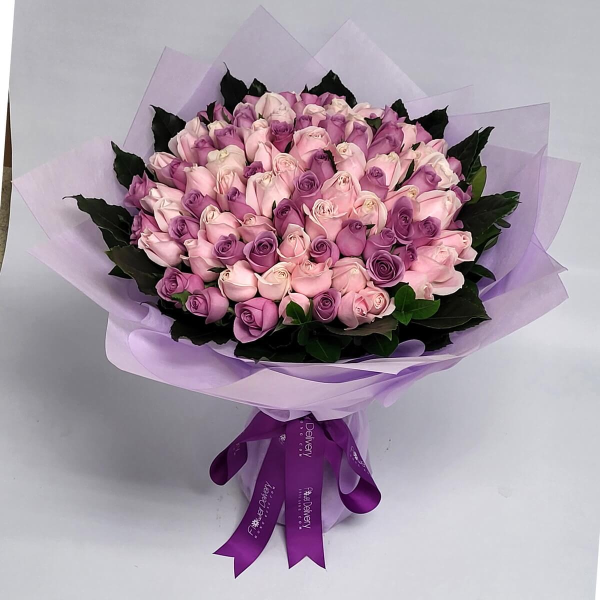 Hand-tied bouquet of lavender and pale pink roses with dark green foliage, wrapped in lilac paper - 紫色及淺粉玫瑰手綁花束，配深綠葉及淡紫包裝紙