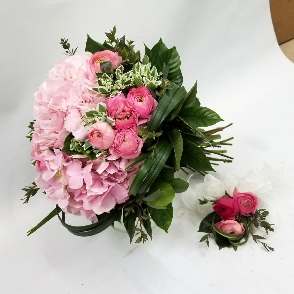 Romantic round bridal bouquet with pink hydrangeas and ranunculus, accented with variegated greenery, matched with a coordinating boutonniere. 浪漫粉紅新娘花球，繡球與洋牡丹搭配斑葉綠植，配以同款襟花。