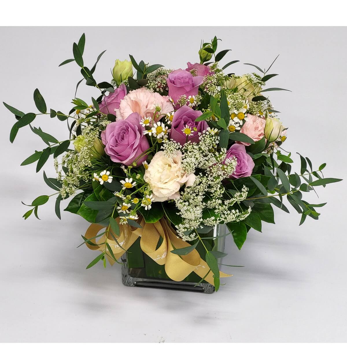 Soft lavender and blush rose mix with chamomile 淡紫與粉色玫瑰融合，搭配洋甘菊與白色小花，綠葉圍繞，金色絲帶點綴玻璃瓶，營造浪漫優雅的田園風情。