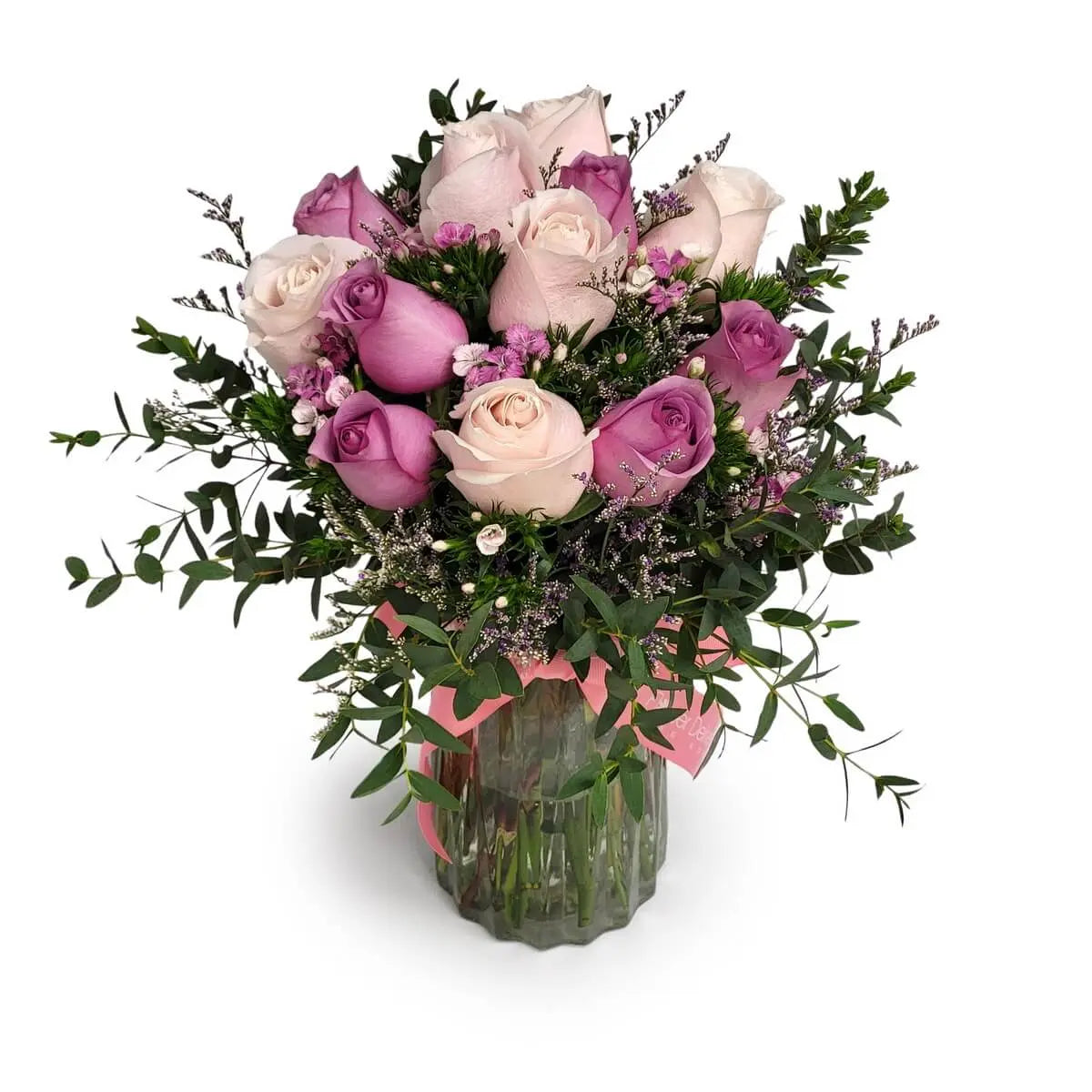 Arrangement of pink and lavender roses with eucalyptus and waxflowers in a vase | 粉紅與薰衣草玫瑰搭配尤加利與蠟花，插於玻璃花瓶中。