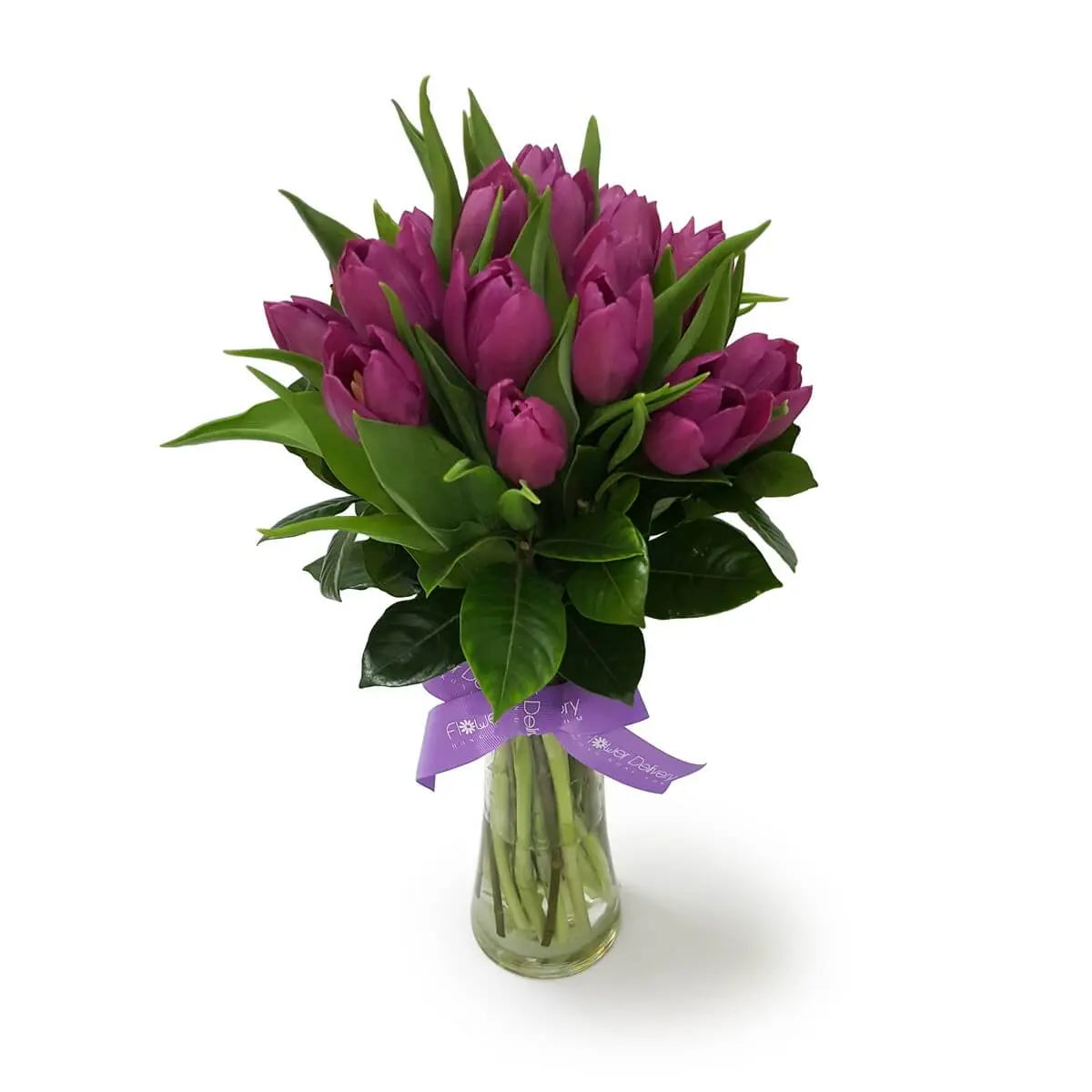 Arrangement of rich purple tulips with vibrant green leaves in a clear glass vase | 飽和紫色鬱金香與嫩綠葉材錯落排布，透明玻璃花瓶中展現簡約花藝美感。