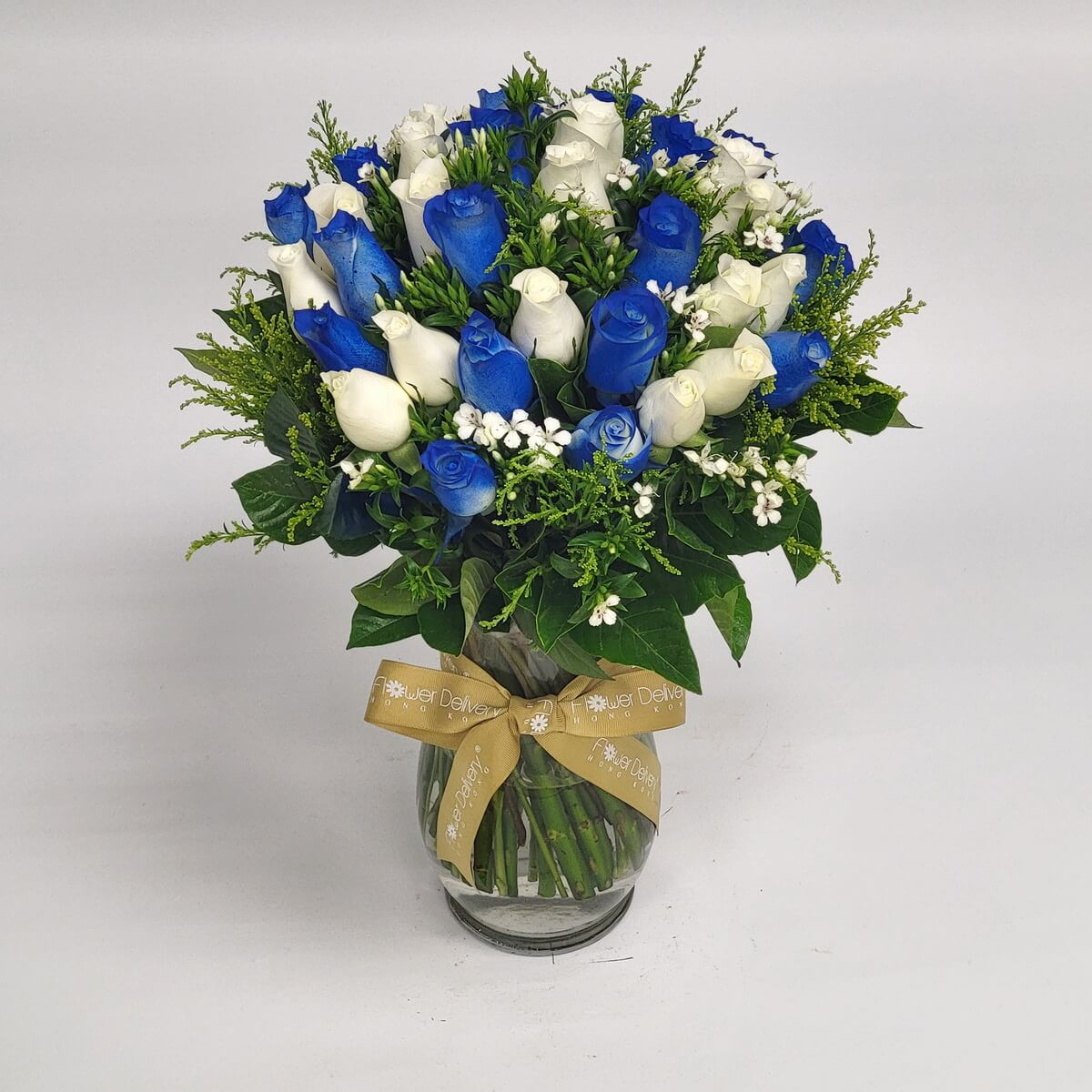 Striking blue and white roses with baby's breath in a vase 鮮豔藍白玫瑰搭配滿天星與綠葉，插於透明玻璃花瓶中，綁上金色絲帶，呈現現代感與高貴氣質，適合祝賀或浪漫場合。