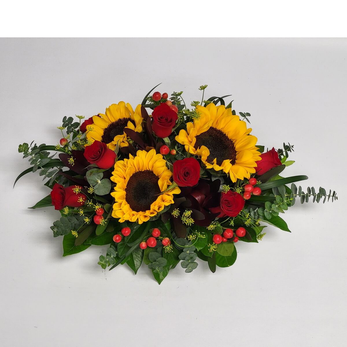 Festive arrangement of sunflowers, red roses, hypericum berries, and assorted greens, ideal for centerpieces – 桌上花藝：向日葵、紅玫瑰、紅豆與各式綠葉組合，氣氛溫馨熱烈