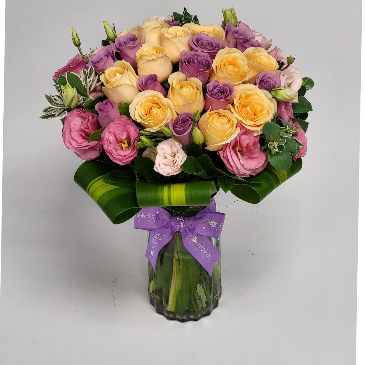 Delicate mix of champagne, lavender, and pink roses with lisianthus in a vase 香檳、紫與粉紅玫瑰交織桔梗花，玻璃瓶承托，綁上紫色絲帶，展現溫柔高雅氣息。