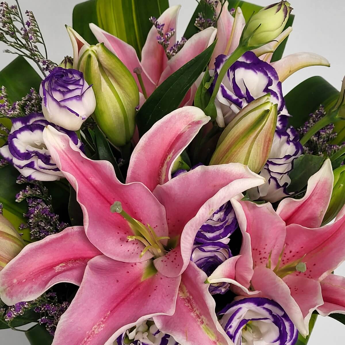 Close-up of vibrant pink lilies with curled petals and purple-edged lisianthus among green buds - 粉紅百合與紫邊洋桔梗及花苞近拍