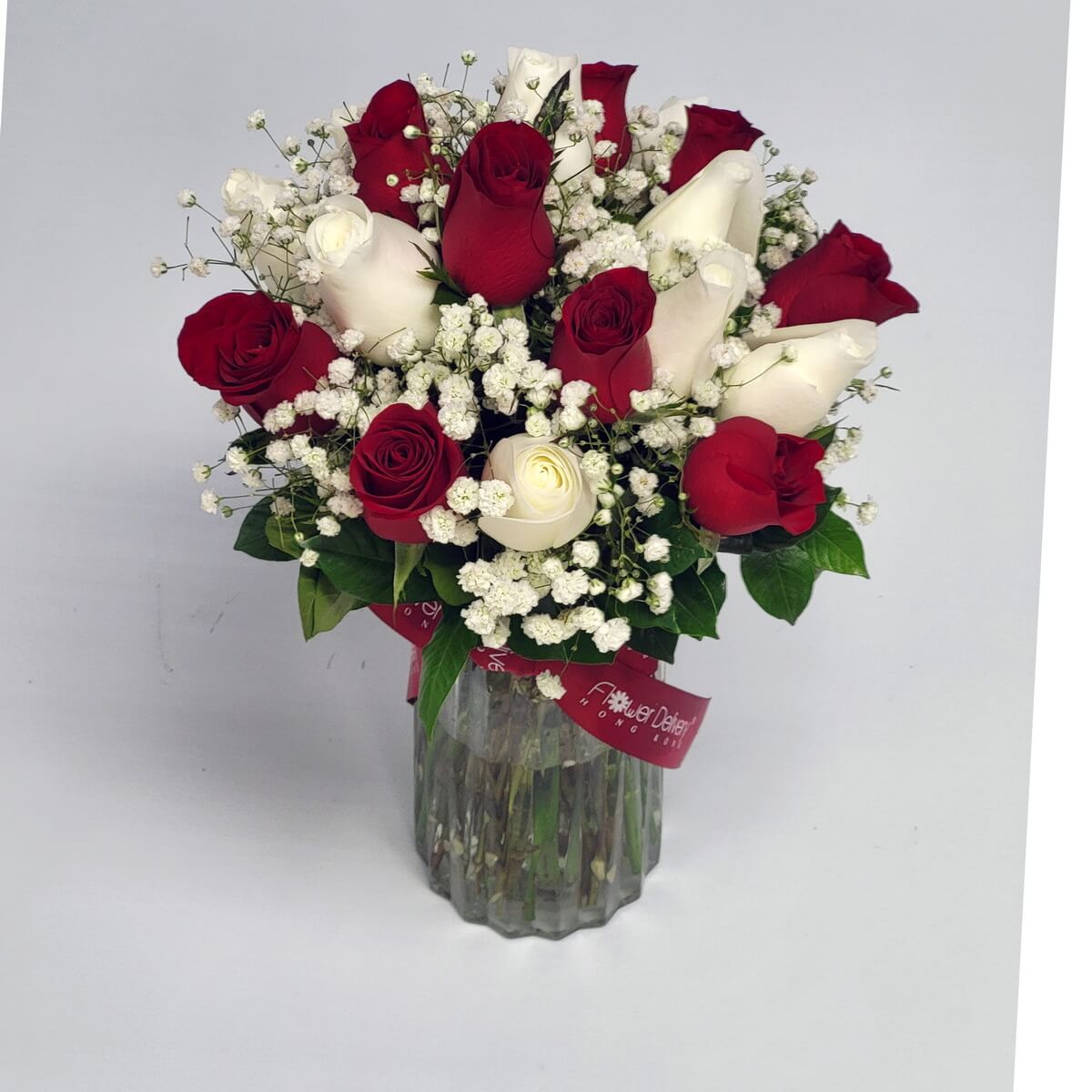 A romantic bouquet of red and white roses accented with baby's breath in a glass vase 紅白玫瑰搭配滿天星，營造浪漫氛圍，擺設於優雅的透明玻璃花瓶中。