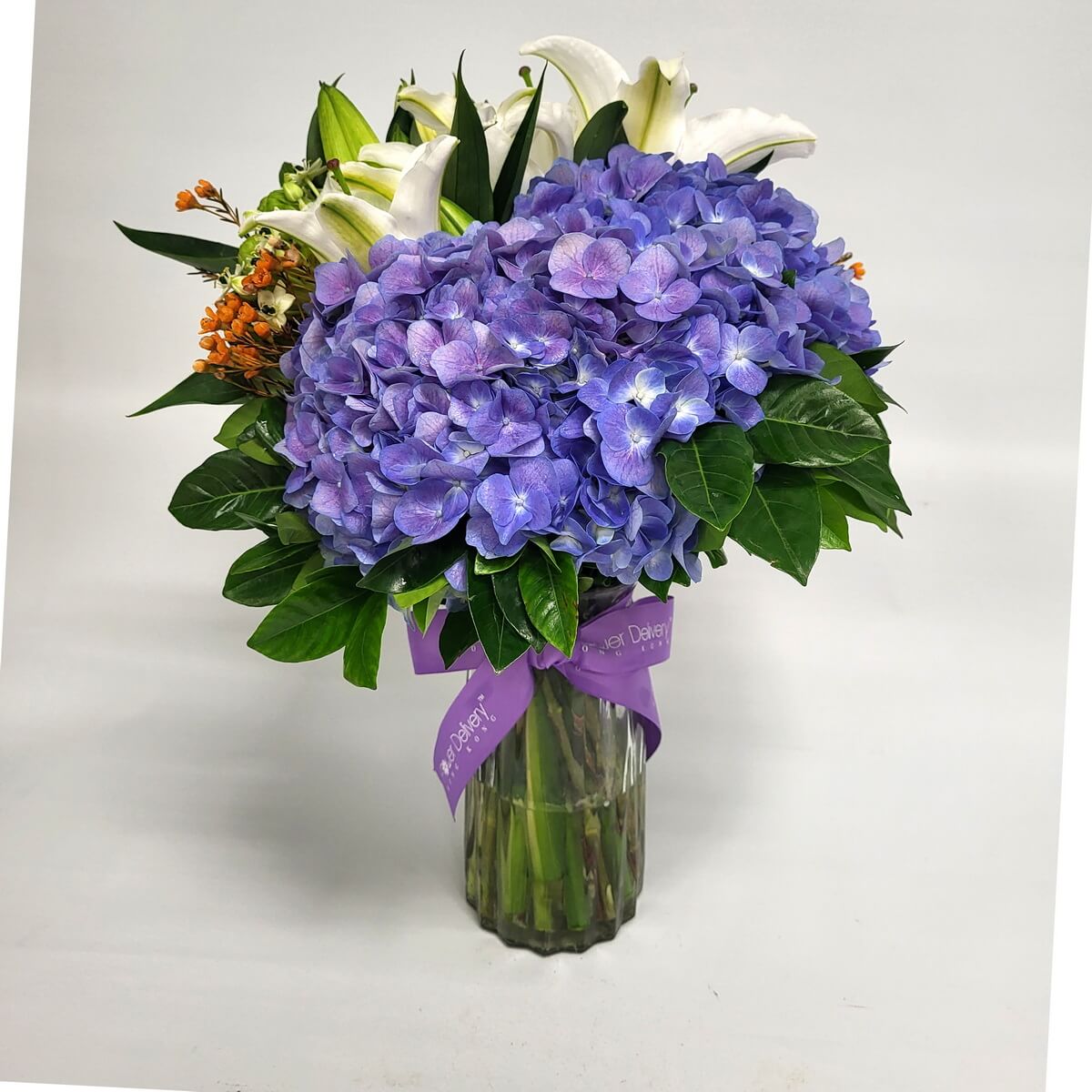 Original photo, vase arrangement of vibrant purple hydrangeas, white oriental lilies, orange filler flowers, and deep green leaves - 紫陽花、白東方百合、橙色配花與濃綠葉的瓶插花束