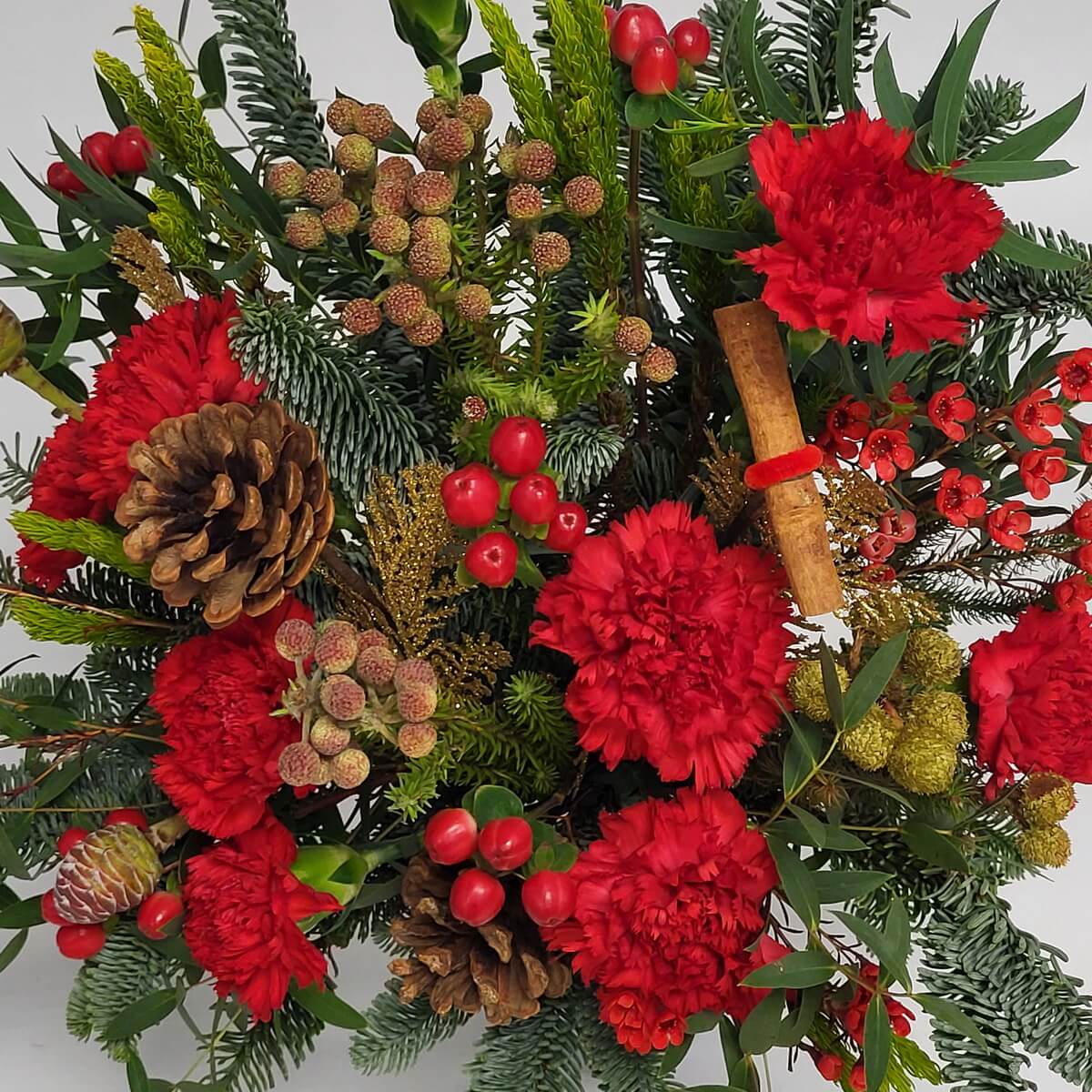 Festive floral arrangement featuring red carnations, pinecones, cinnamon stick, waxflowers, red hypericum berries, textured pods, pine and gold leaves - 花藝設計含紅康乃馨、松果、玉桂棒、蠟花、紅繡球果及金葉