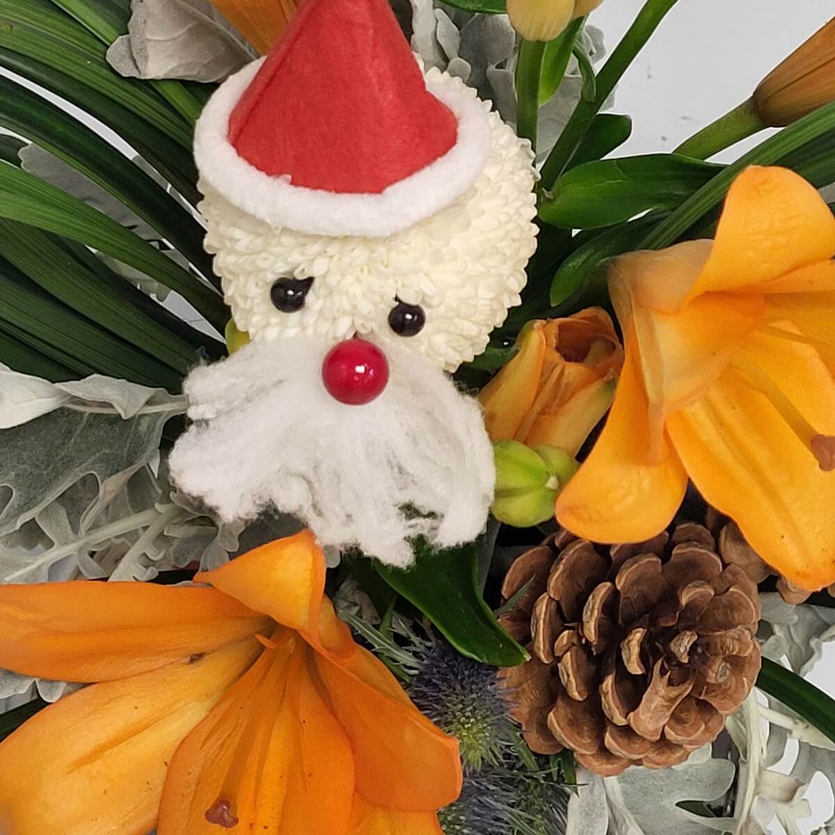 Close-up of Santa head made from white button chrysanthemums with orange lilies and pinecone - 白乒乓菊聖誕老人配橙百合與松果特寫