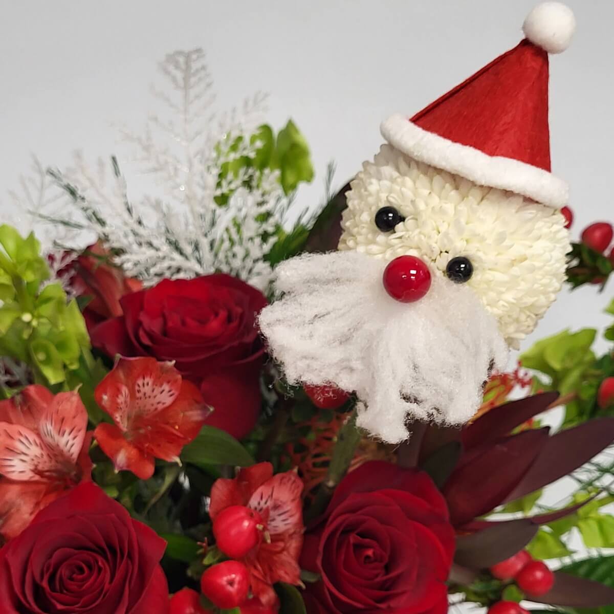 Santa face crafted from white button chrysanthemums, accented by red roses, coral alstroemeria, red hypericum berries, bells of Ireland, and silver foliage - 白乒乓菊聖誕老人造型配紅玫瑰、紅金魚花、繡球果、愛爾蘭鈴與銀葉特寫